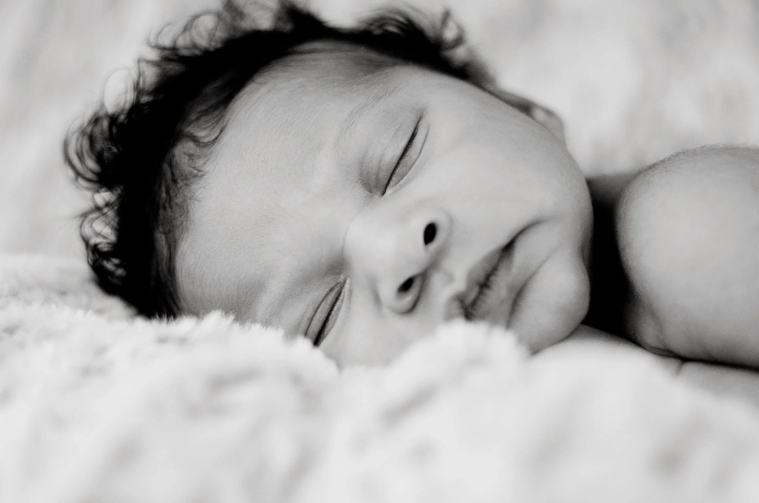 Black and white photo of infant baby sleeping peacefully.