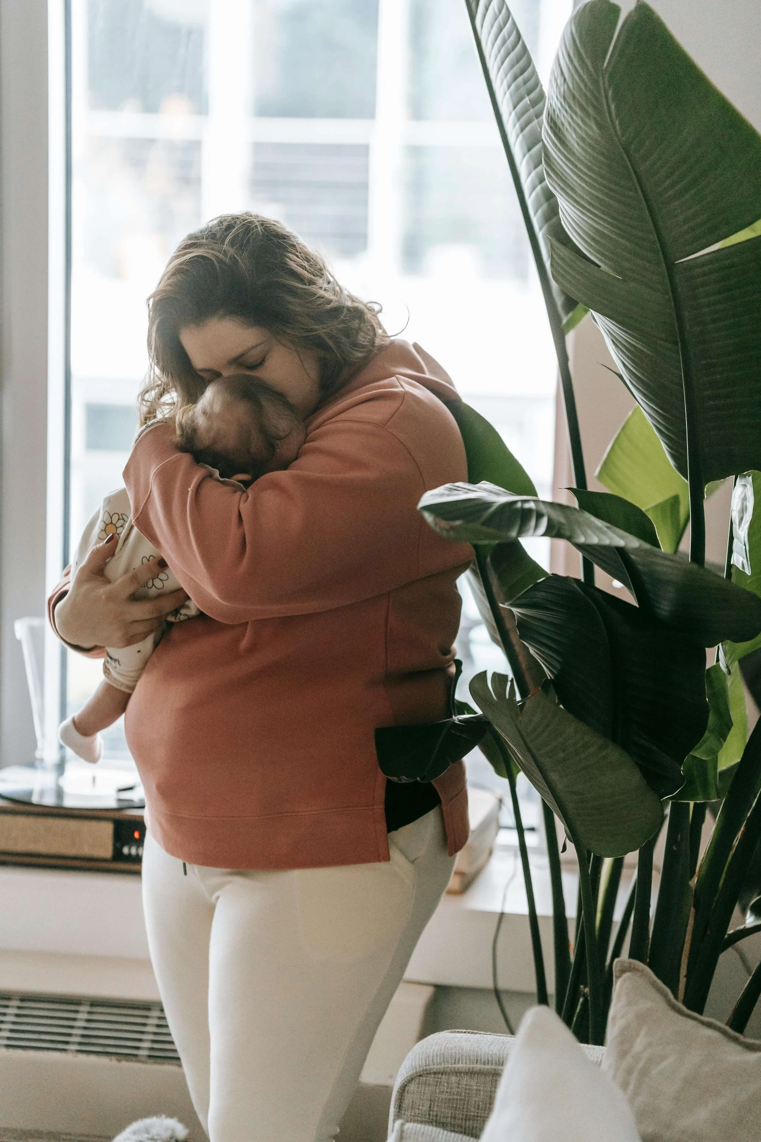 New mom cradles her infant in her arms and kisses the baby's face.