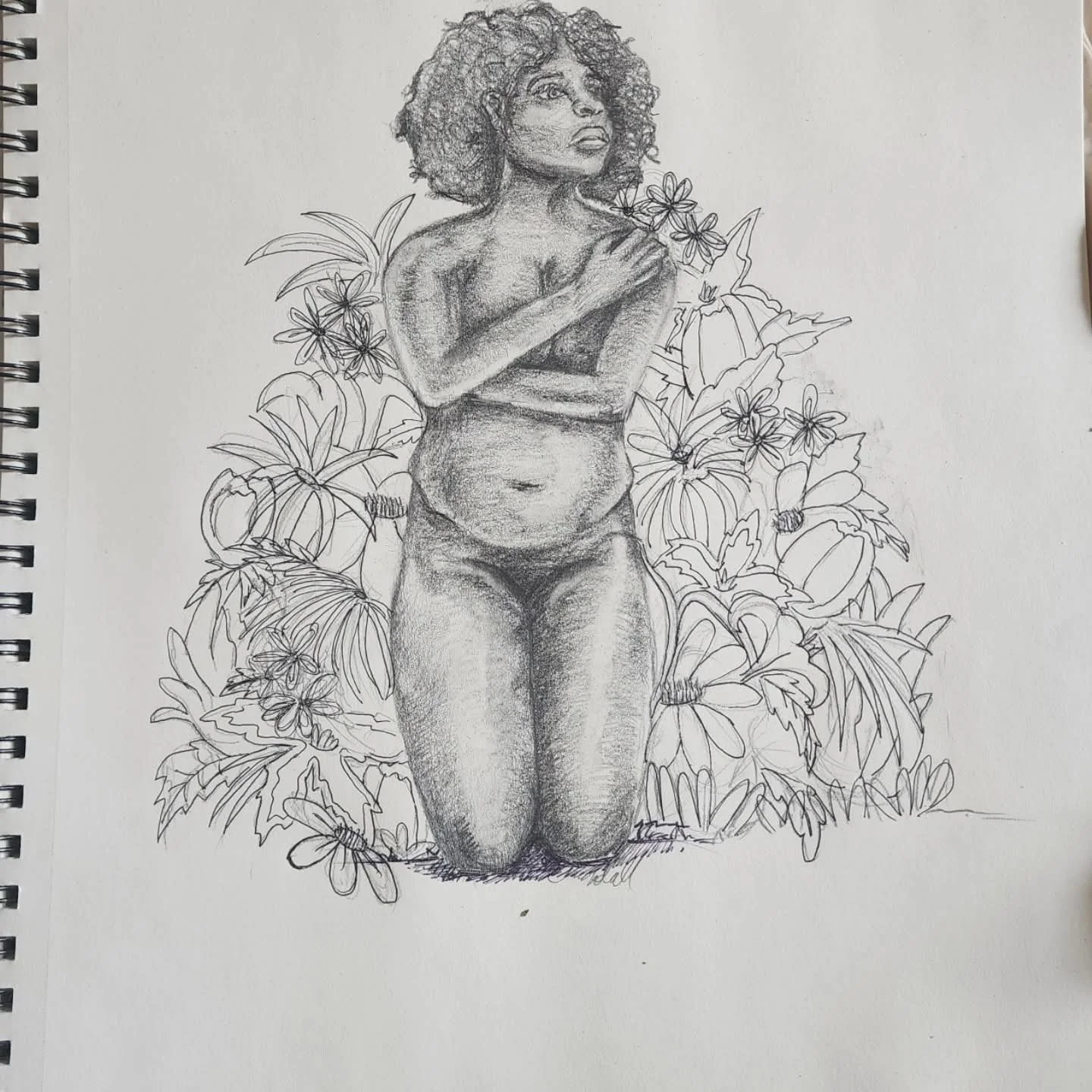 Sketch of a woman with curly hair, kneeling with hands over her chest, surrounded by flowers and foliage.