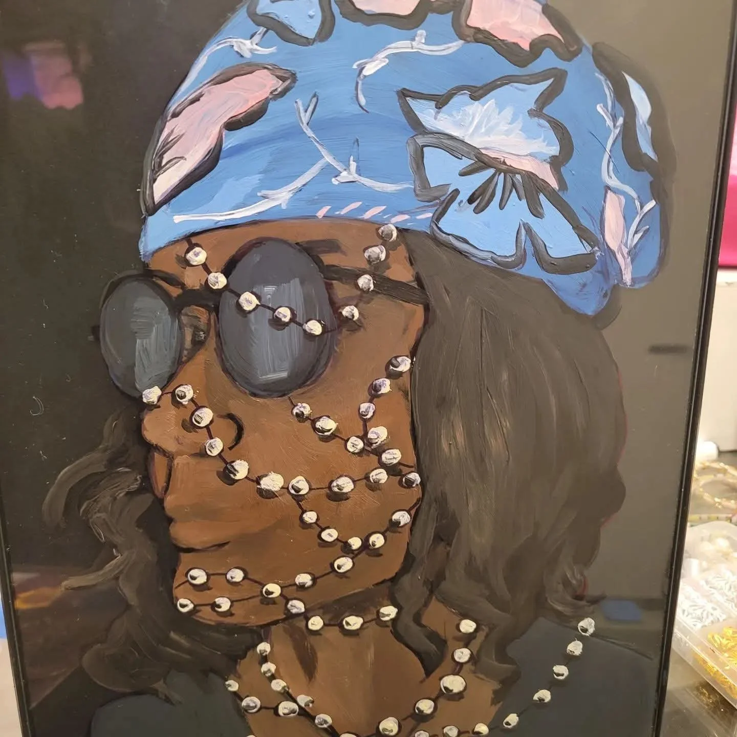 Painting of a woman wearing sunglasses and multiple pearl necklaces, with a blue headscarf adorned with large flowers.
