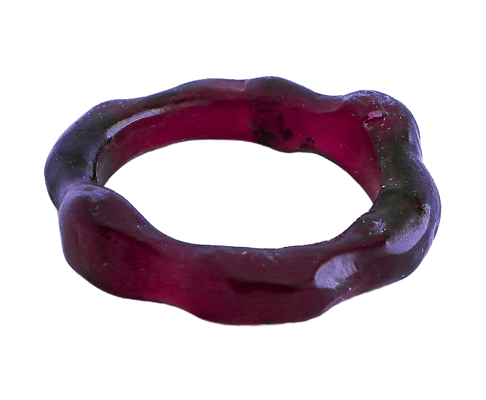 A dark-colored, irregularly shaped hand carved wax ring.