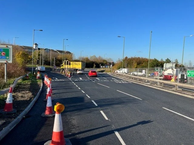 Roadwork on a highway with orange cones, construction vehicles, and traffic.