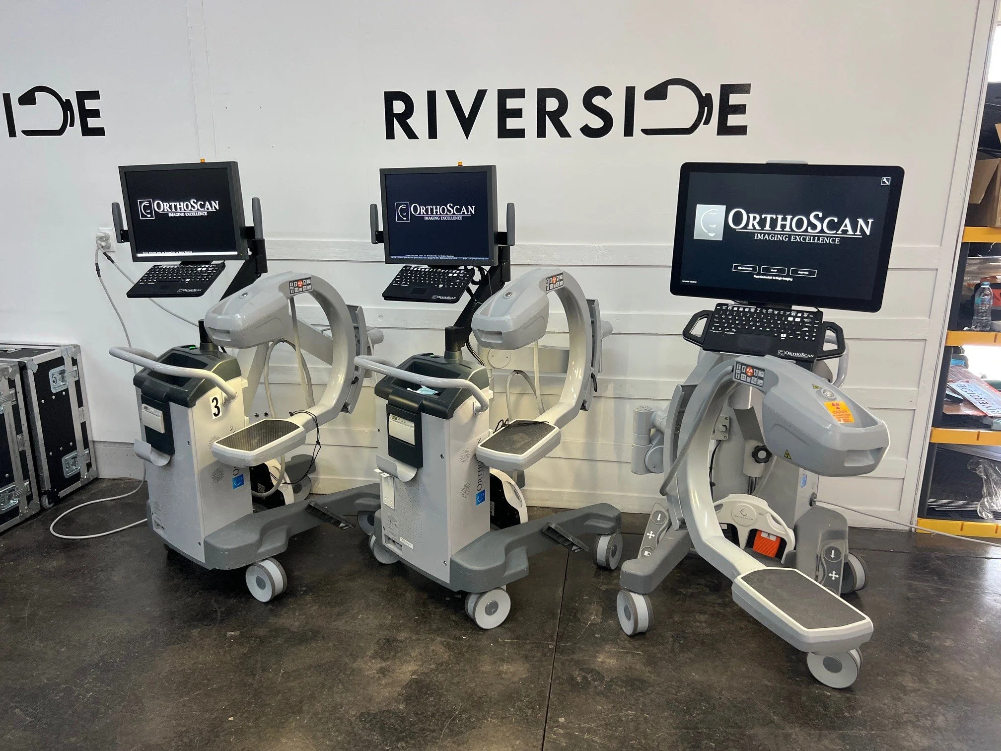 Three medical imaging machines with monitors displaying 'OrthoScan' and 'Imaging Excellence' in a clinical or medical setting.