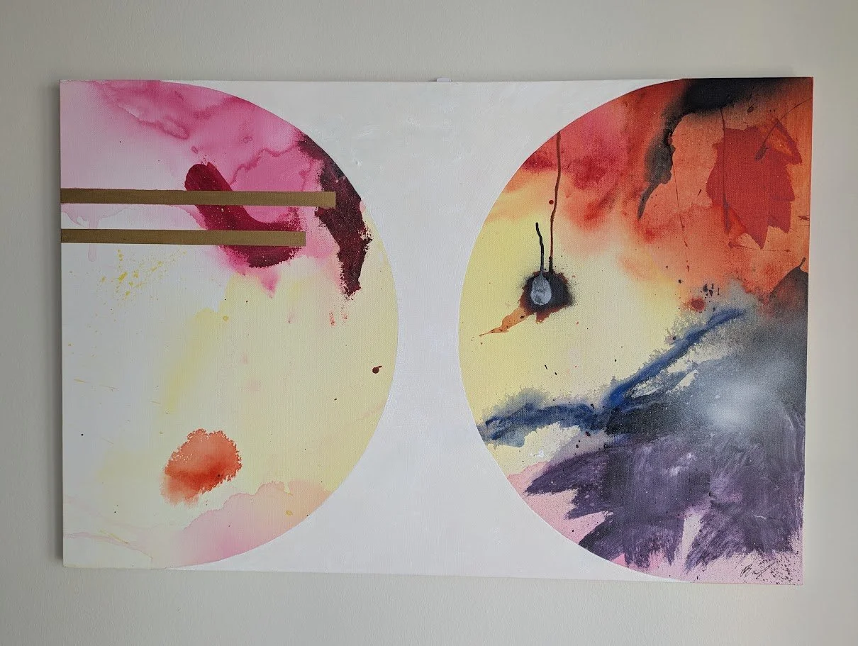 Abstract watercolor painting with two large overlapping circles featuring splashes of pink, orange, purple, and black, with three horizontal gold lines on the left side.
