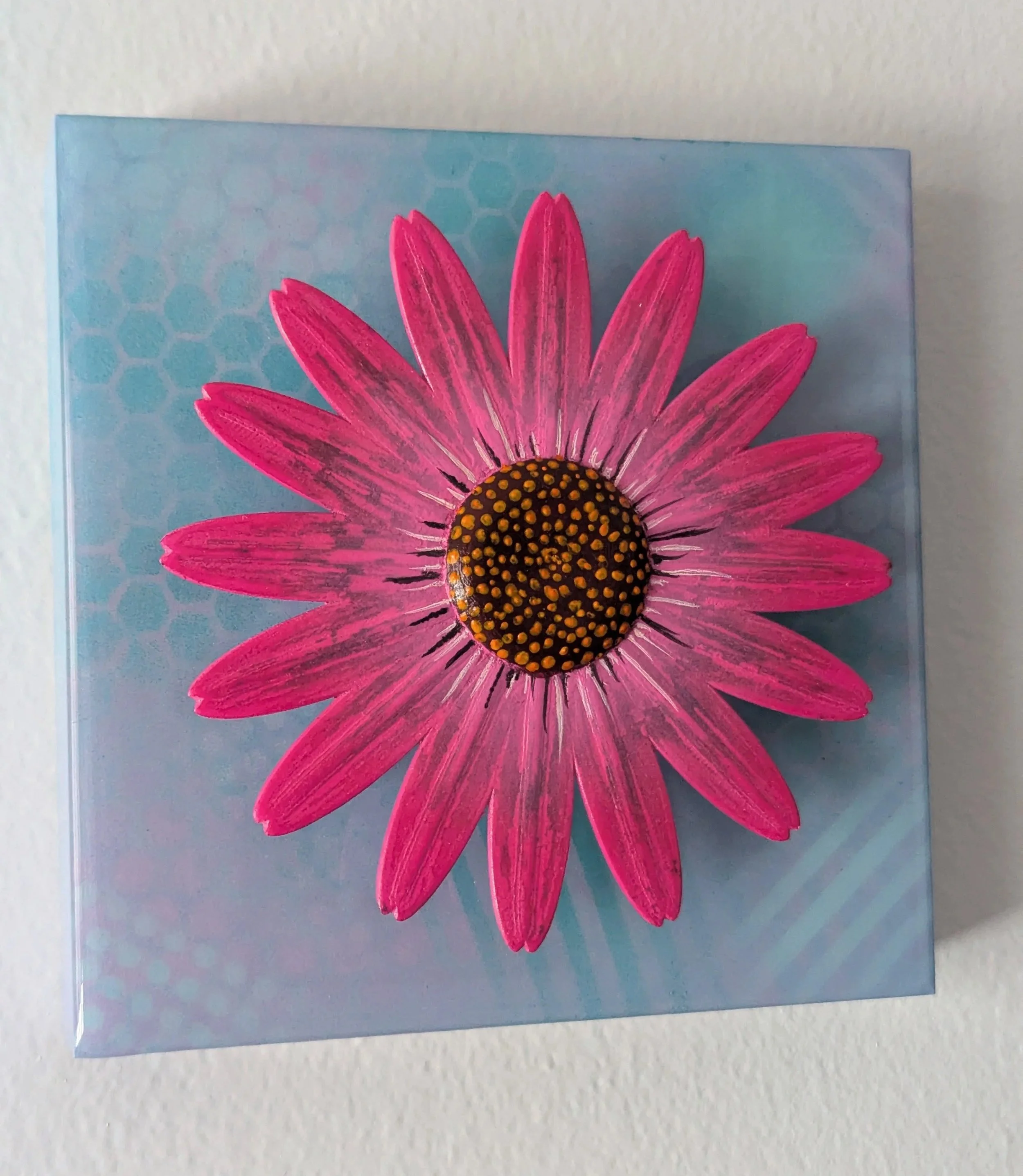 Blue painting with an elevated pink flower popping out of the painting