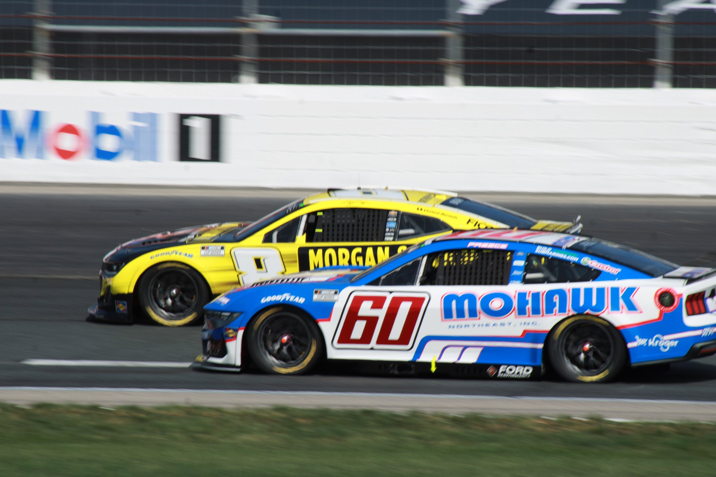 Two race cars on a track, one yellow and one blue, competing in a race.