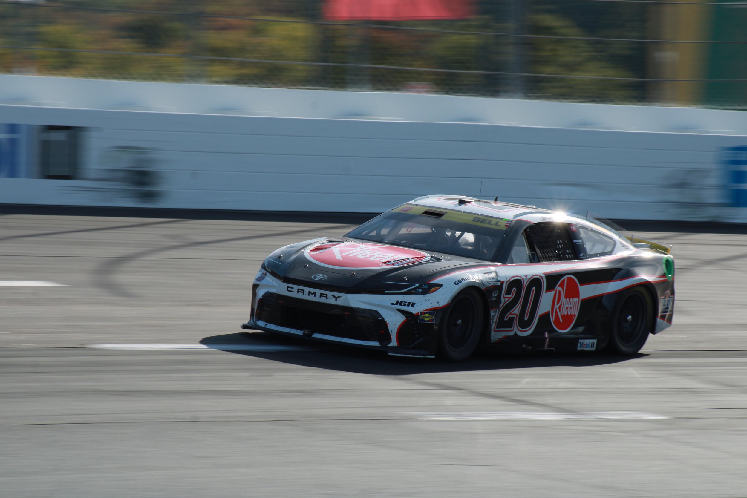 A black, white, and red racing car with the number 20 on its side driving on a race track.