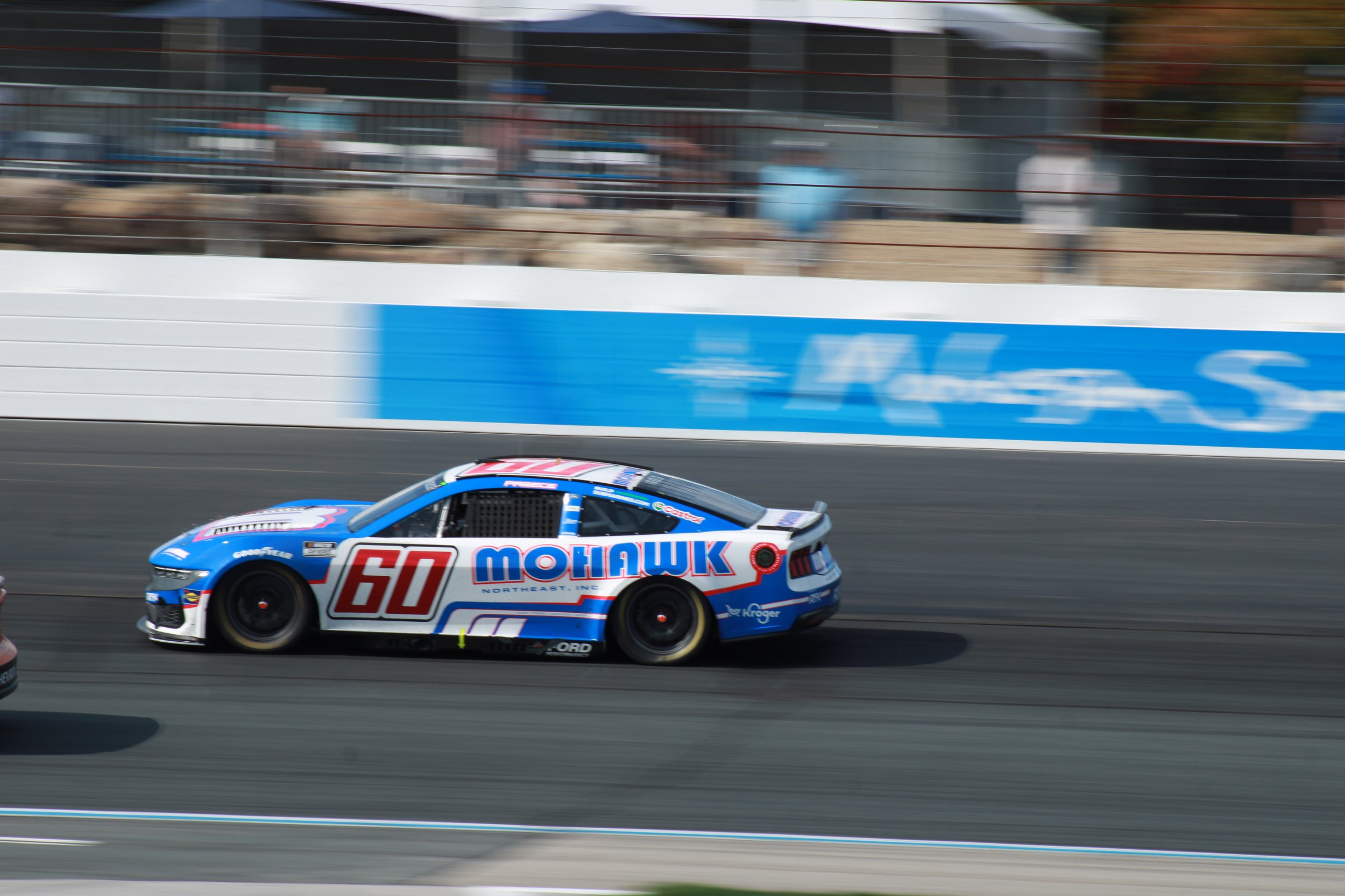 A race car with the number 60 and MoHawk branding on the side, racing on a track with a blurred background.