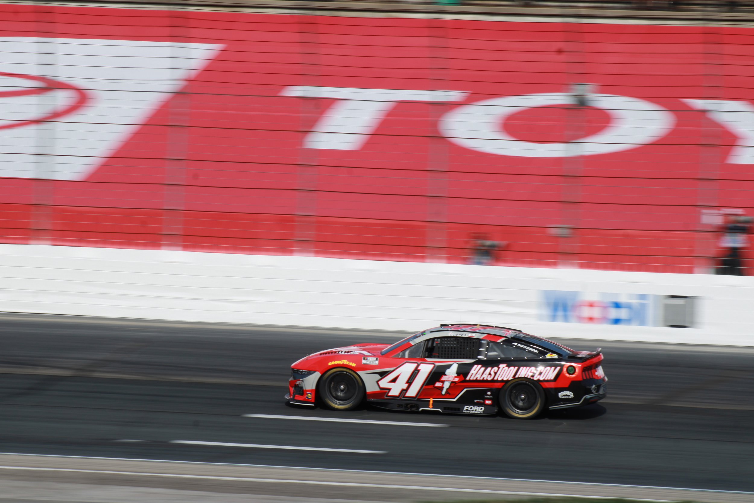 A red and black race car with the number 41 on the side moving on a racetrack with a red wall and large target logo in the background.