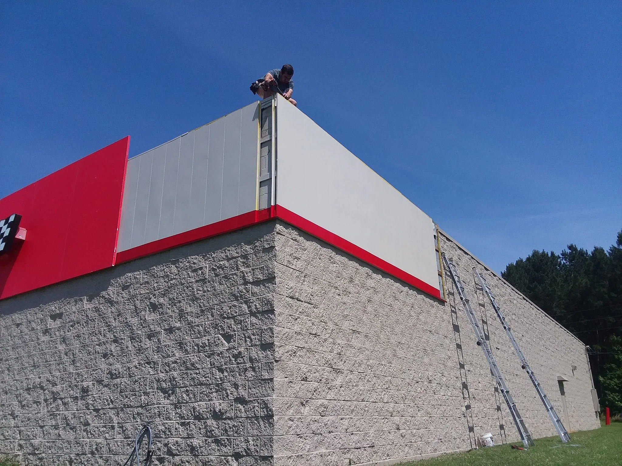 Man on the rooftop excluding bats from a building's exterior wall.