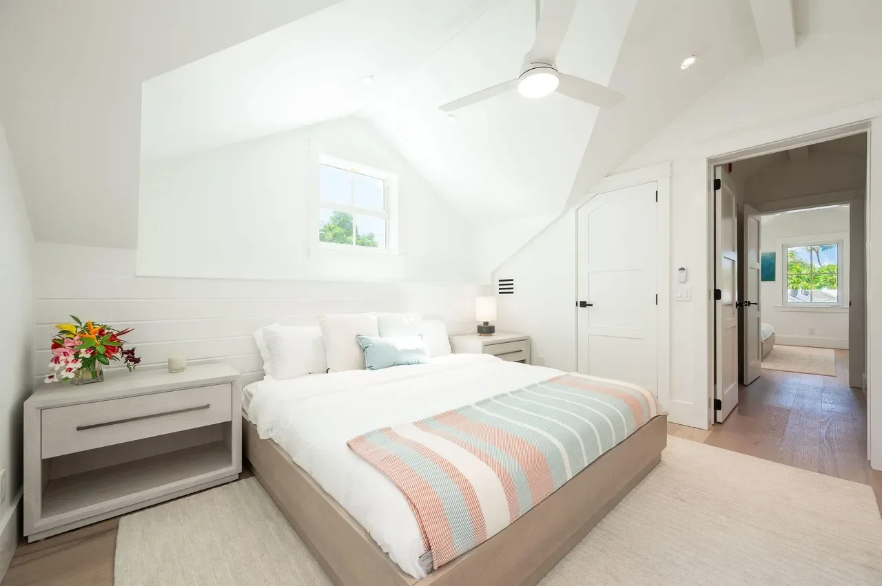 Coastal Key West bedroom with soft neutral bedding, light wood furniture, shiplap wall detail, and bright natural light inspired by Florida Keys living.