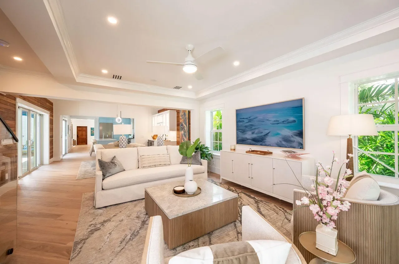 Open-concept Key West living room with modern coastal furniture, light wood floors, white sofa, tropical greenery, and indoor-outdoor flow designed for Florida Keys living.