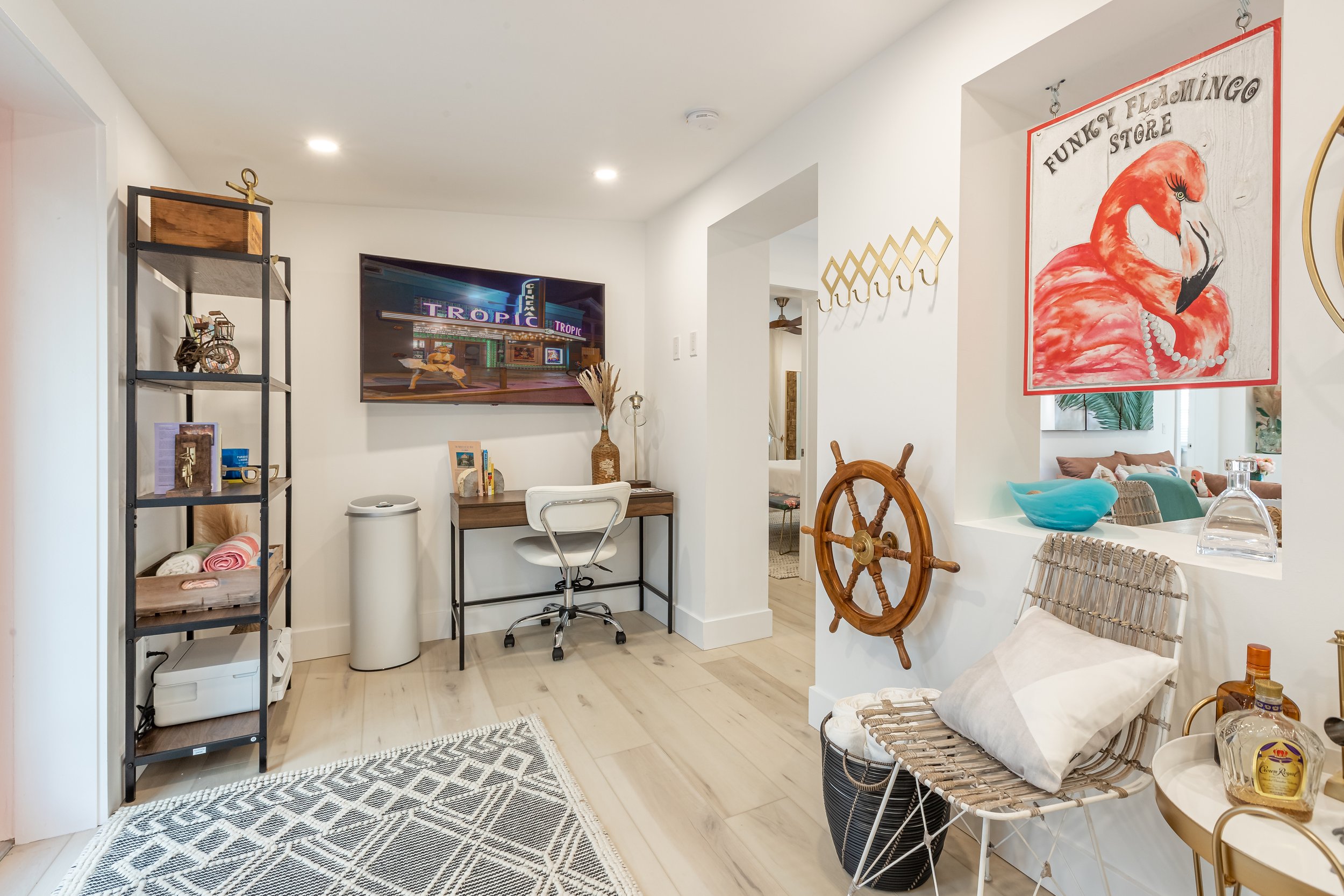 Key West coastal entryway with small home office nook, rattan accents, nautical decor, and playful island-inspired artwork.