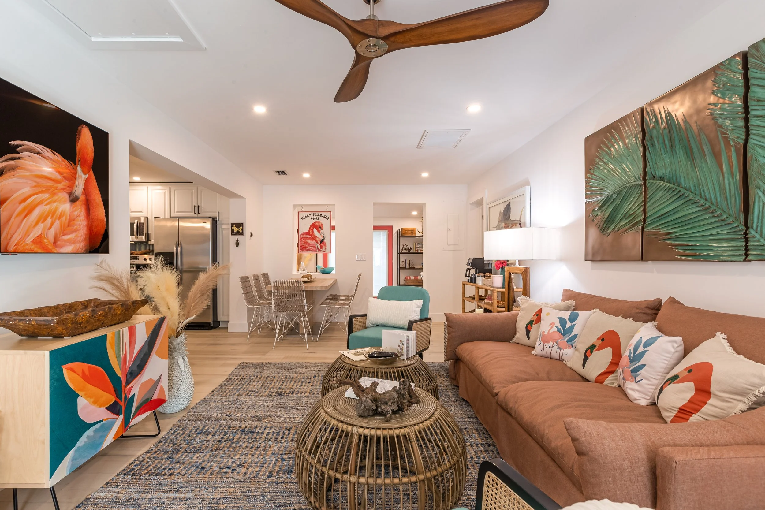Modern Key West living room with warm neutral sofa, woven coffee tables, ceiling fan, coastal artwork, and relaxed Florida Keys style.
