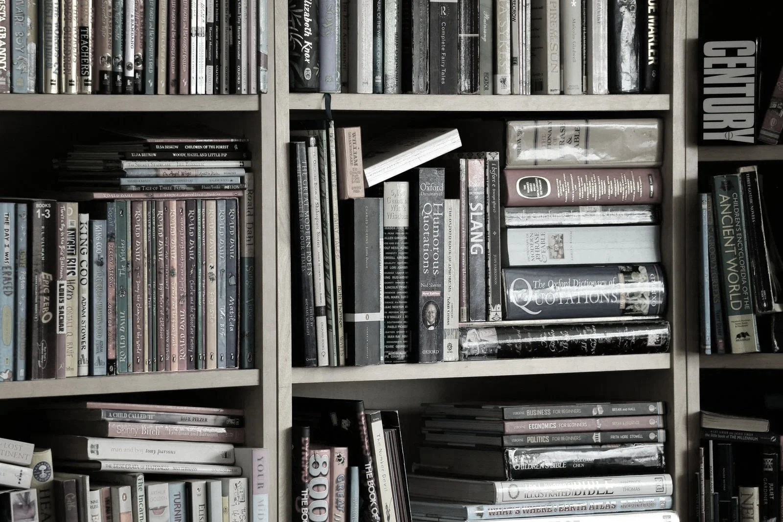 A bookshelf filled with various books of different sizes and colors, organized on multiple shelves.