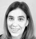 A black-and-white portrait of Julia Moreno - a woman with long, dark hair smiling at the camera.