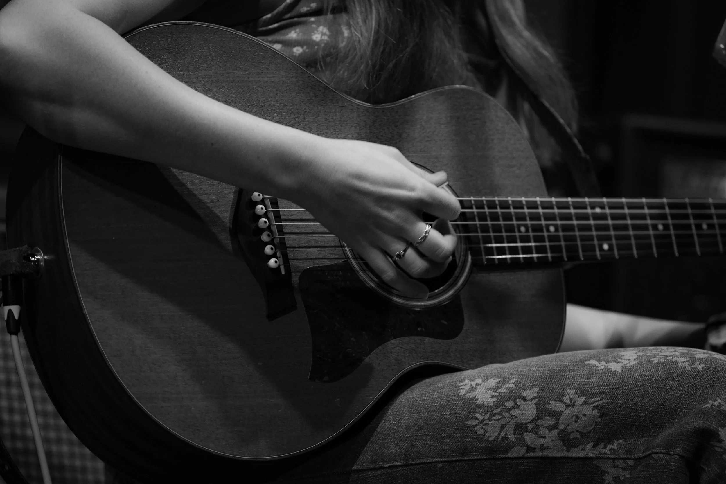 Louise Parker performing live at a country pop gig in Essex, playing acoustic guitar during an intimate singer-songwriter set.