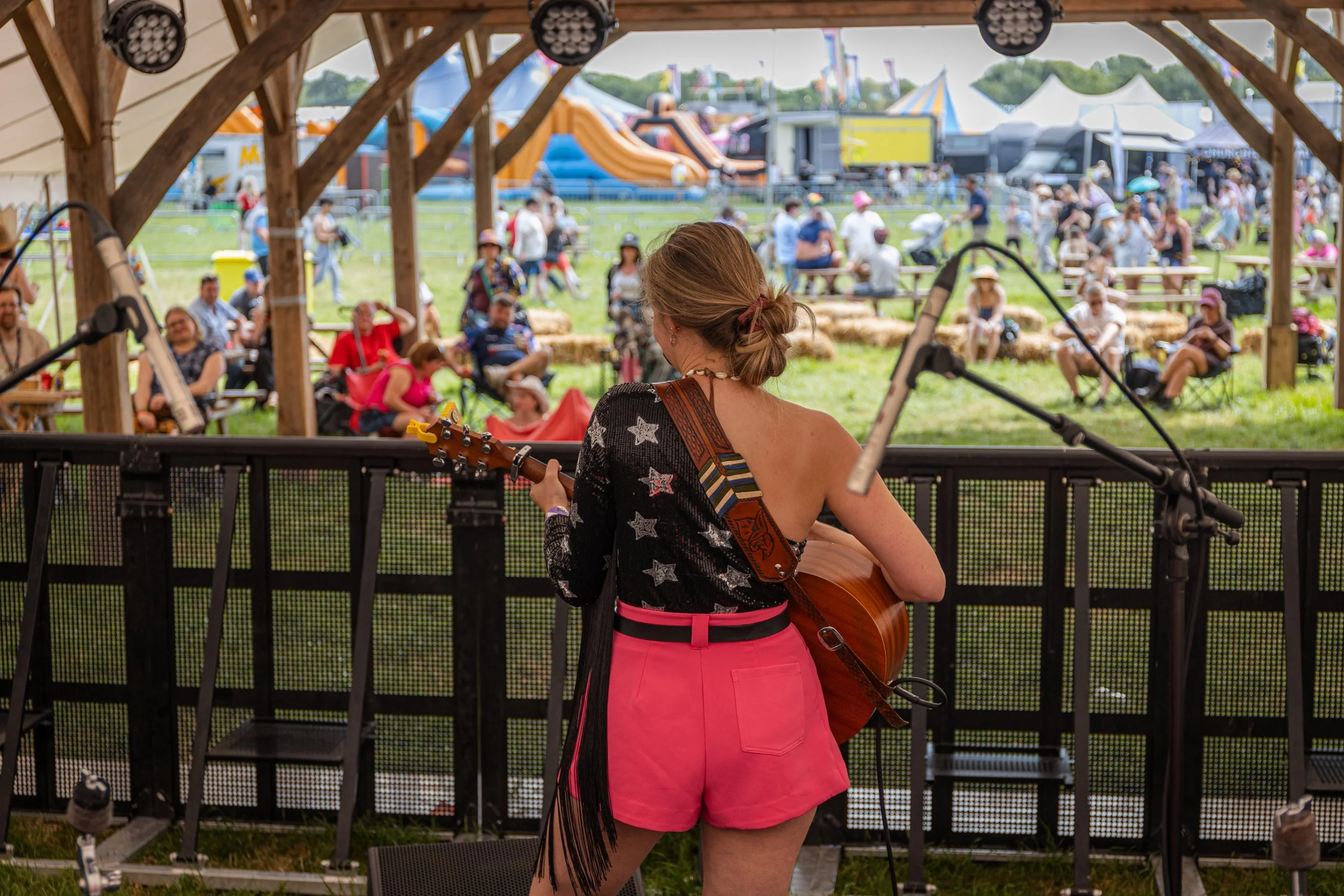 Louise Parker performing a live country pop music set at a UK festival, entertaining audiences with original songs and acoustic guitar during a summer outdoor concert in Essex.