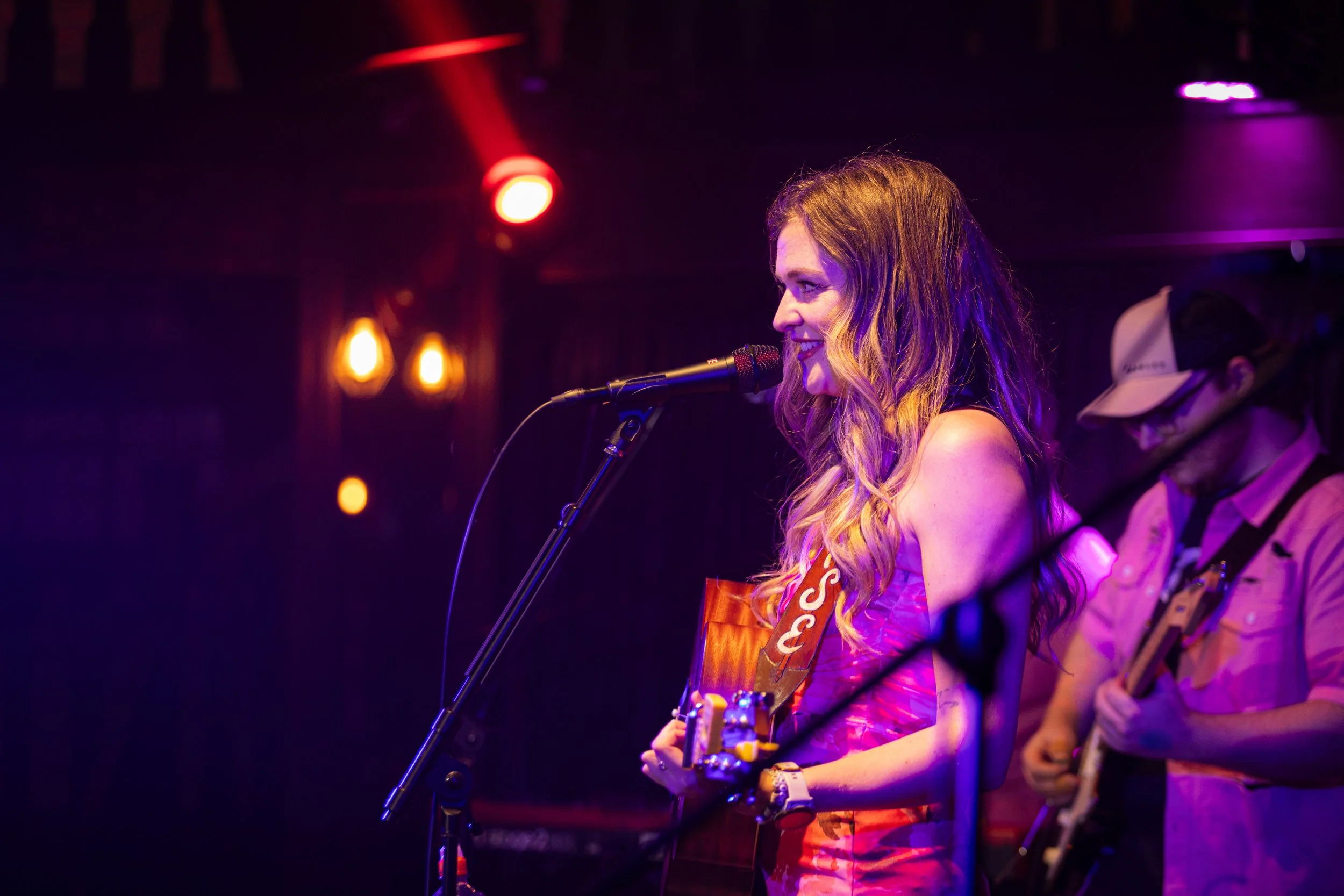 Louise Parker performing live at a country pop gig in Essex, singing and playing acoustic guitar during an intimate UK live music show.