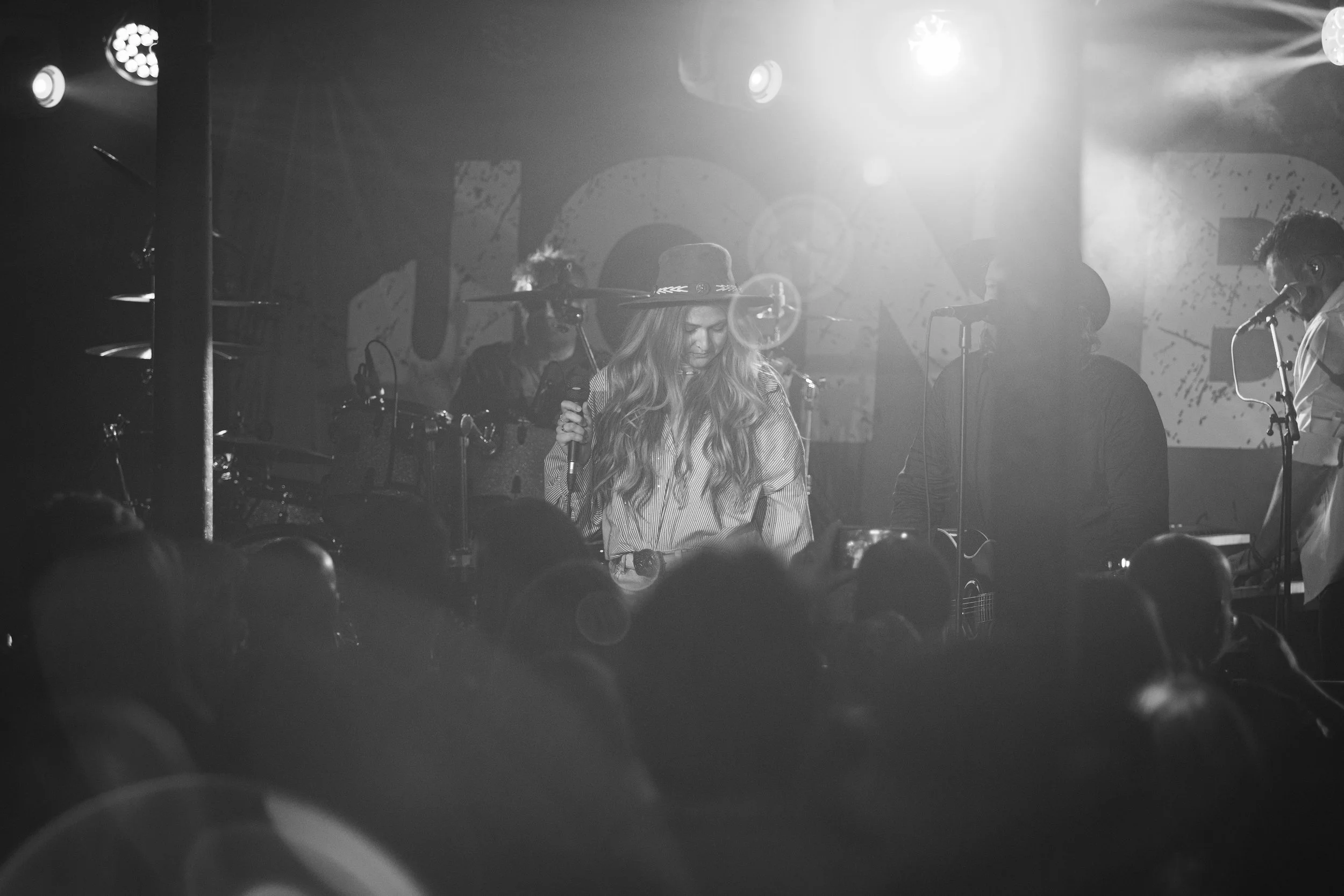 Louise Parker performing live on stage with her band at a UK country pop concert in front of a packed audience.