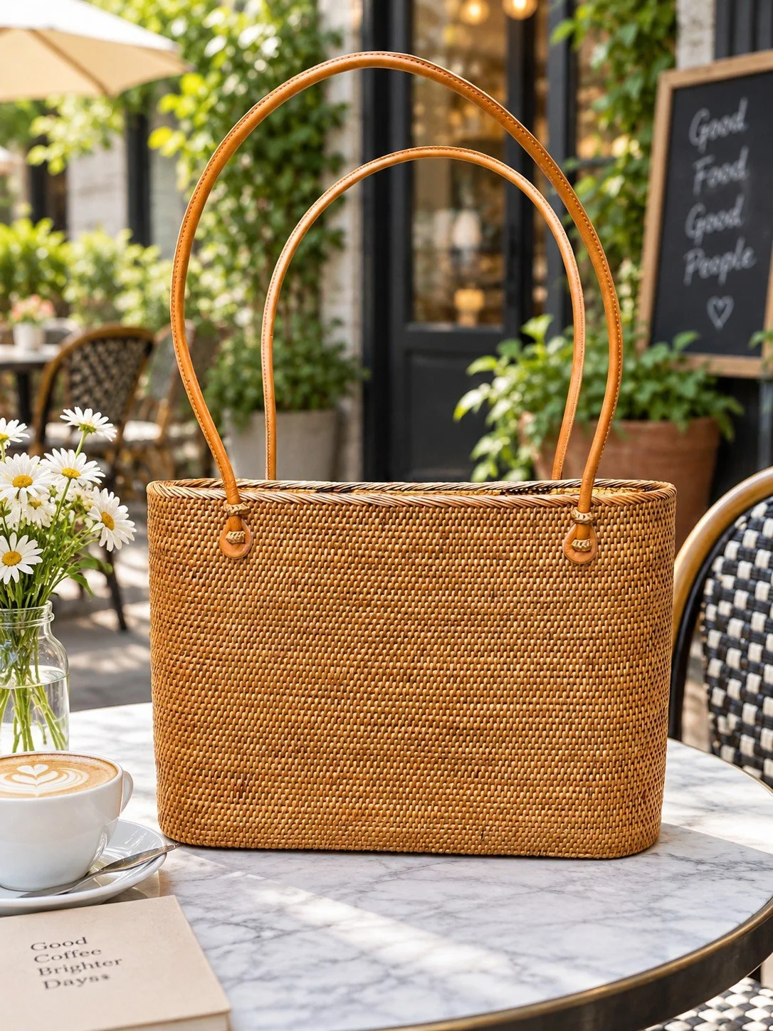 Big Straw Bag large woven shoulder tote, front view at a cafe