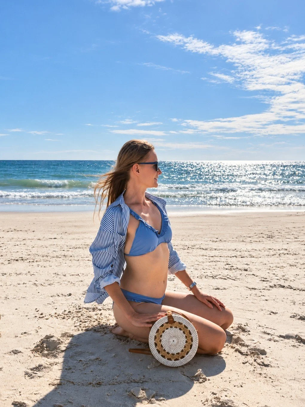 Woman posing with the Twisted Vines white round rattan crossbody at the beach