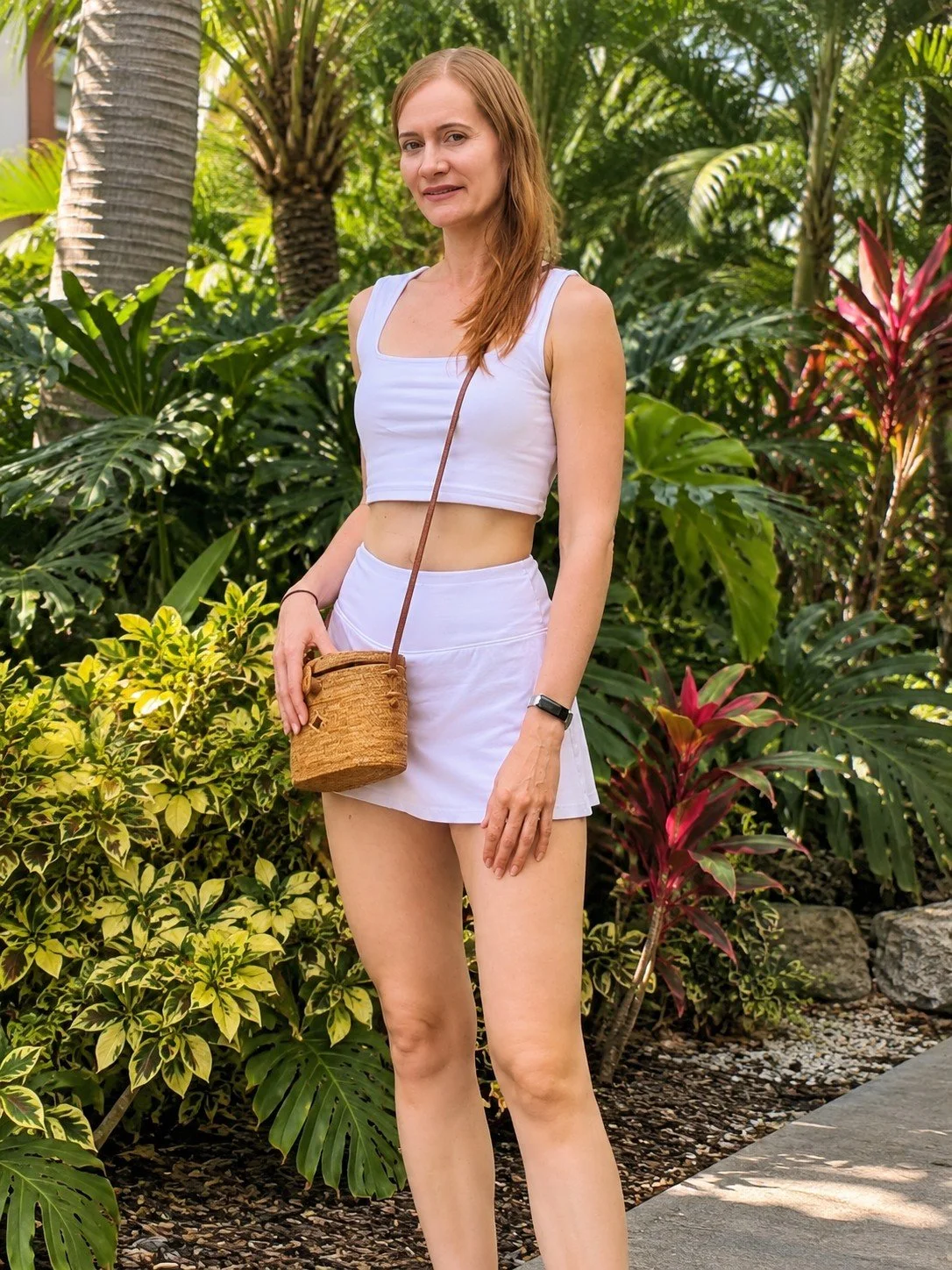 Woman wearing the Clutch and Go mini oval rattan crossbody in garden party