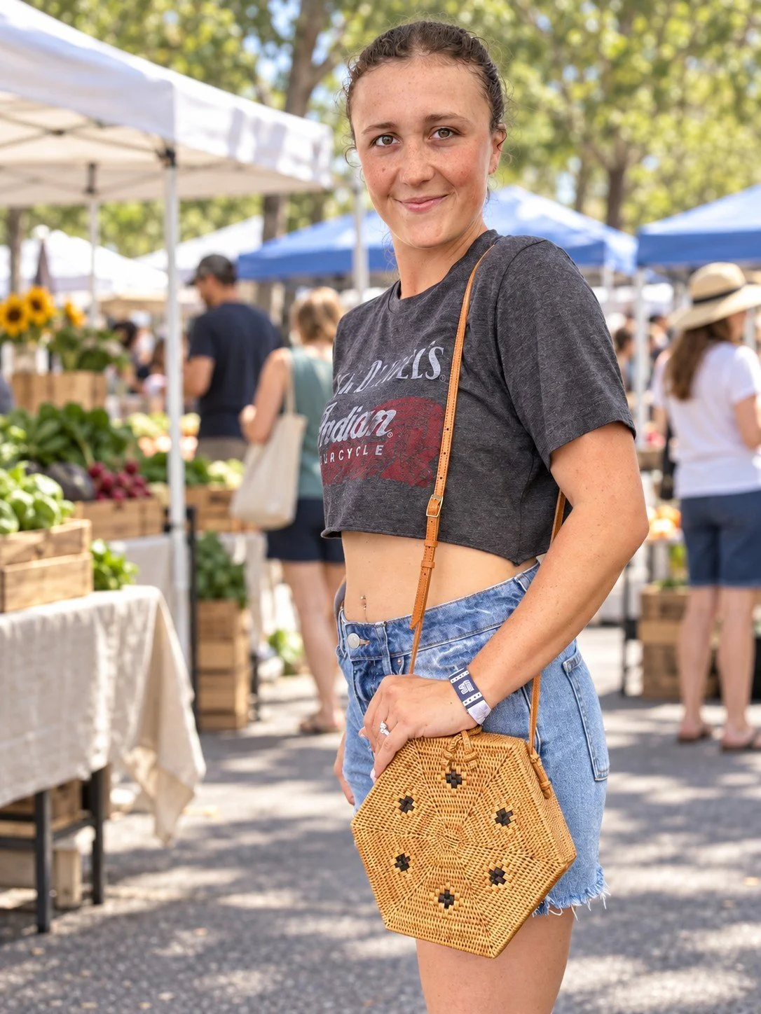 Woman wearing the Rattan Rhapsody hexagon rattan crossbody at the farmers market
