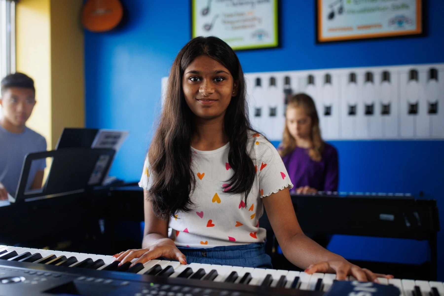 3 teens in a piano class each at a keyboard