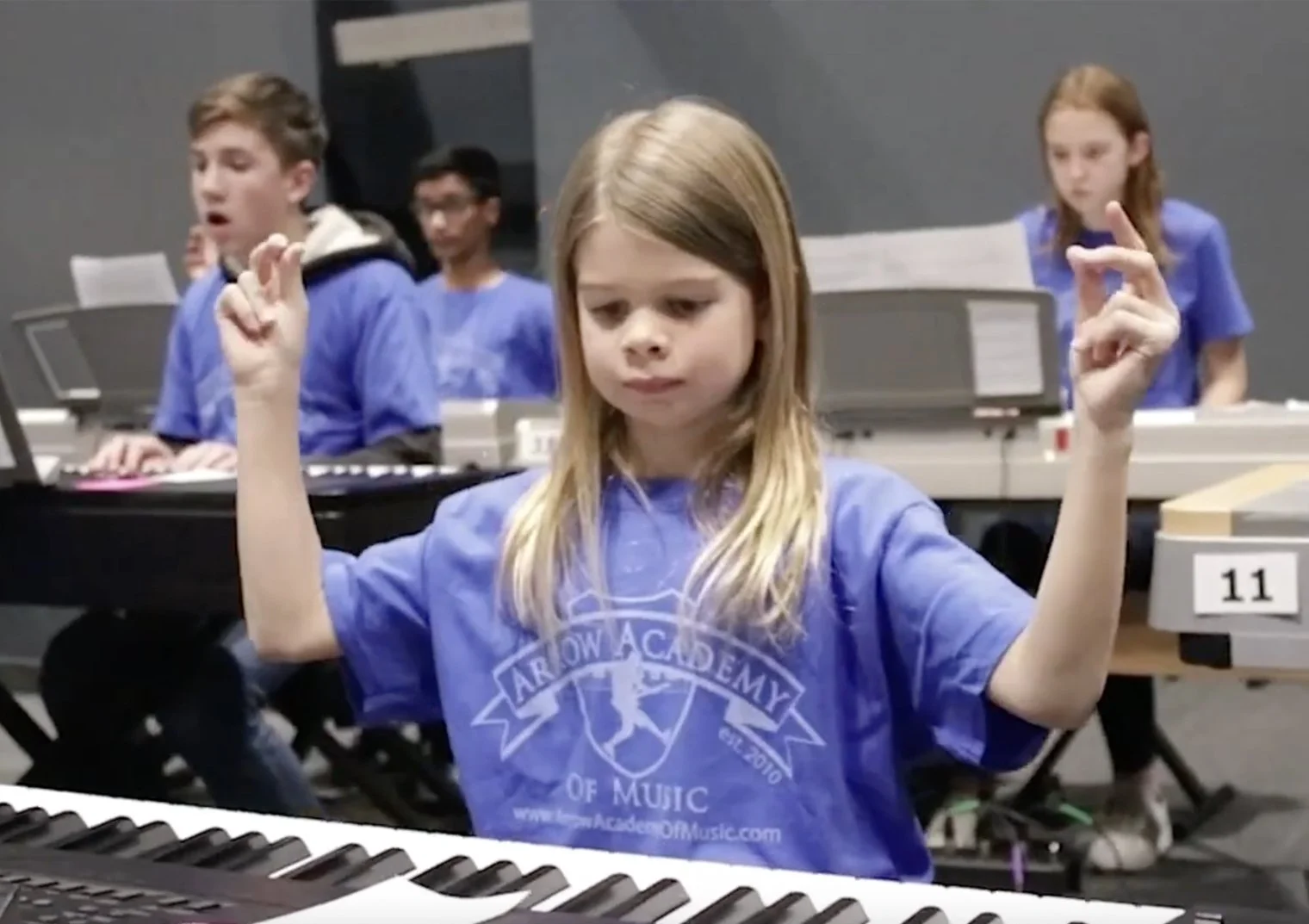 piano students sitting at keyboards performing together on stage