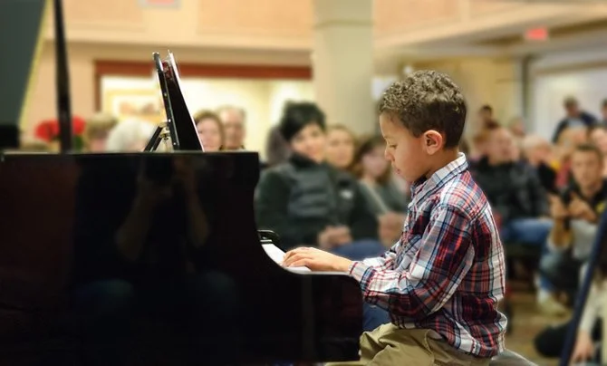young boy performing at piano concert