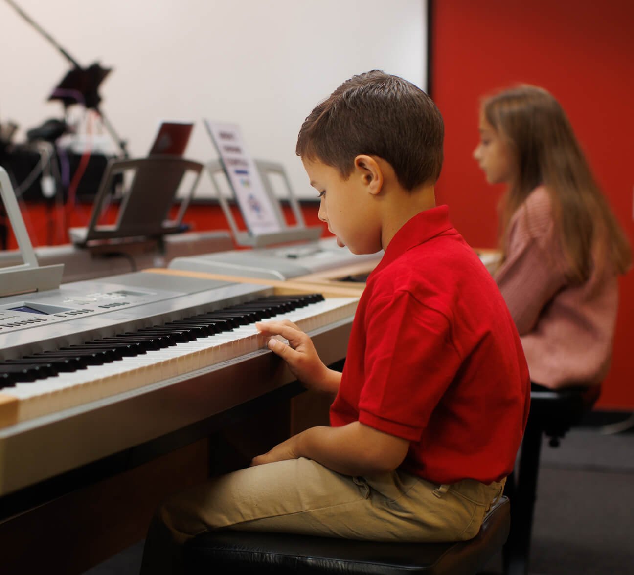 young boy and girl in piano lesson at keyboards