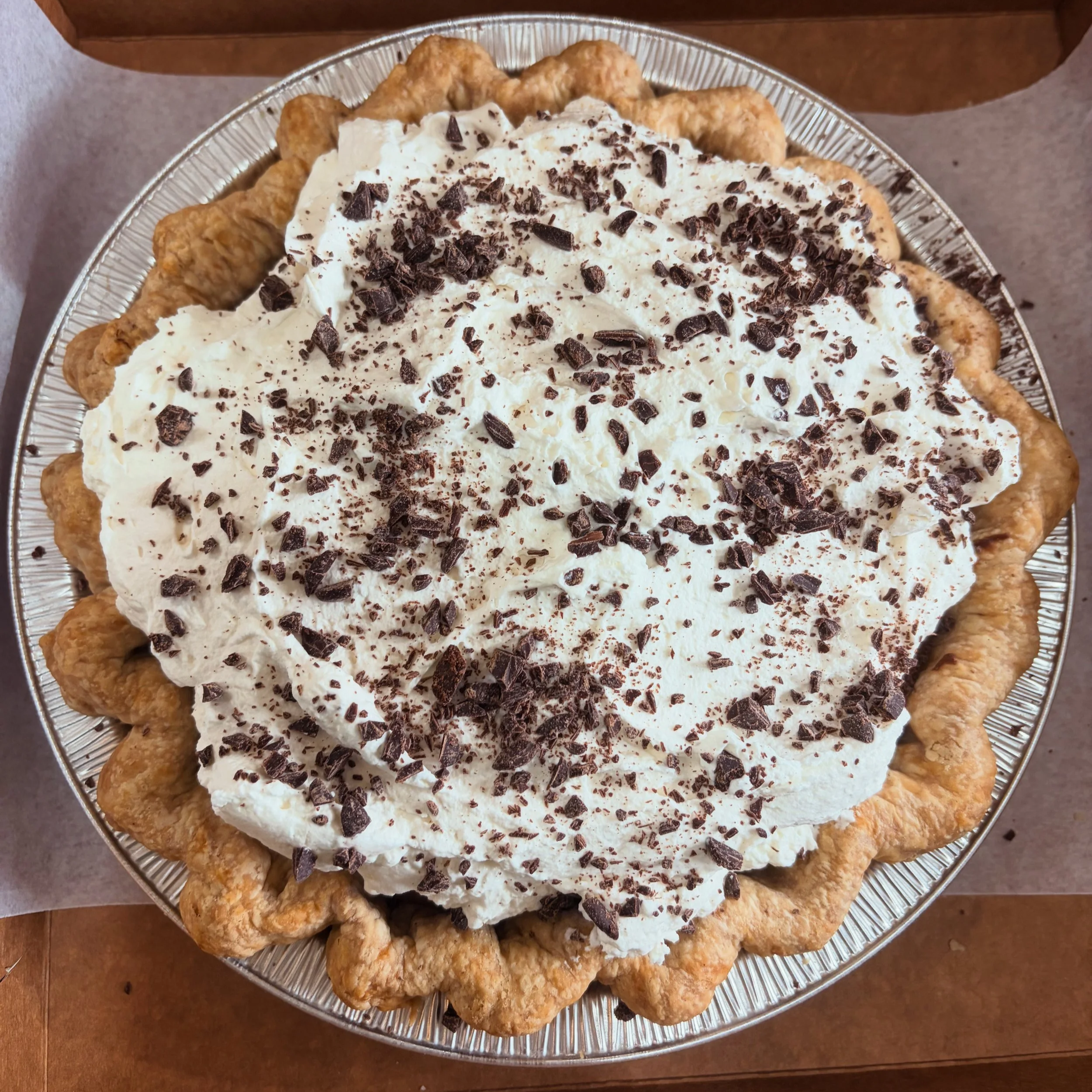 Close up of a pie with whipped cream and chocolate shavings