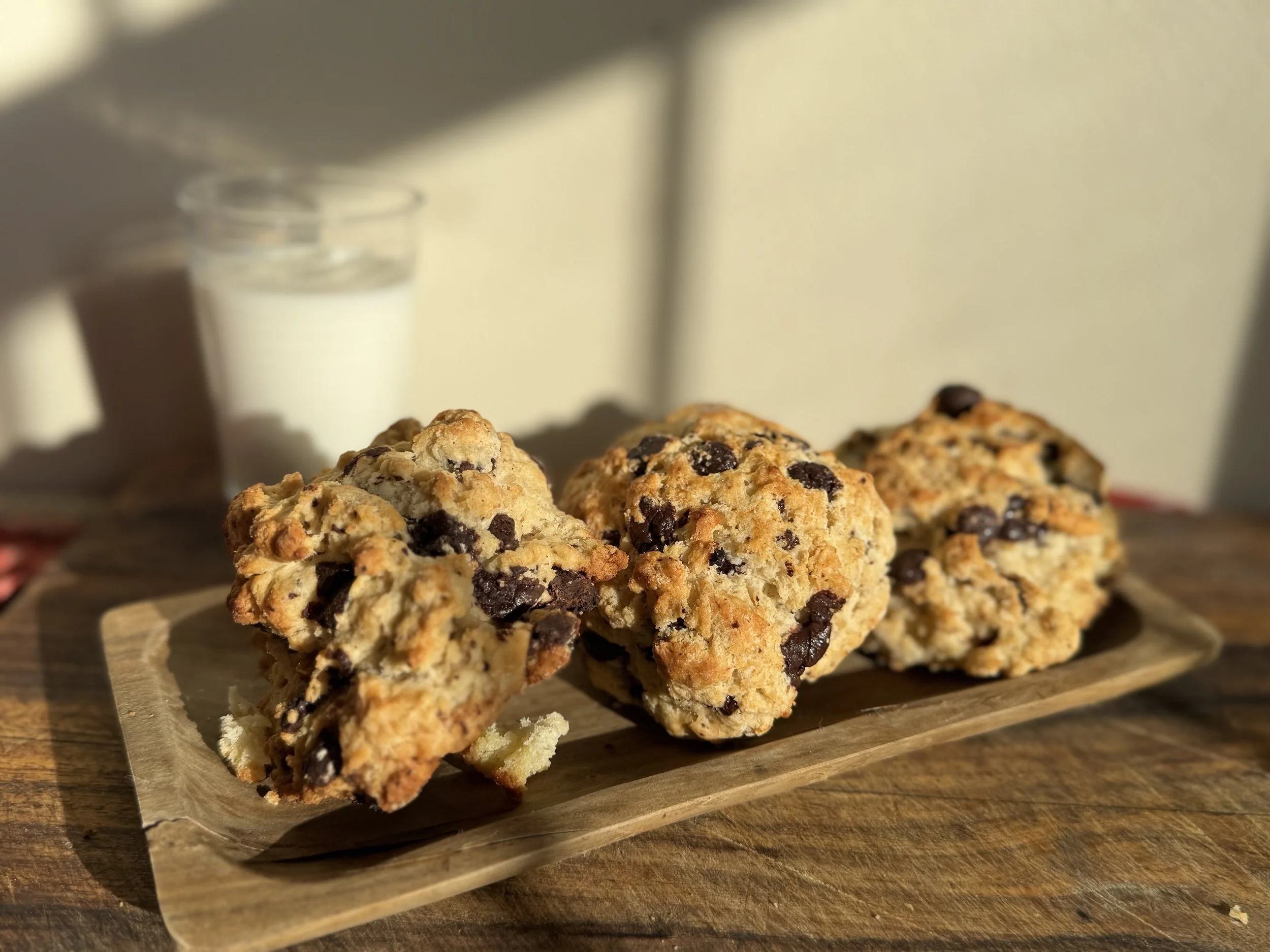 Three chocolate chip cookies on a wooden tray
