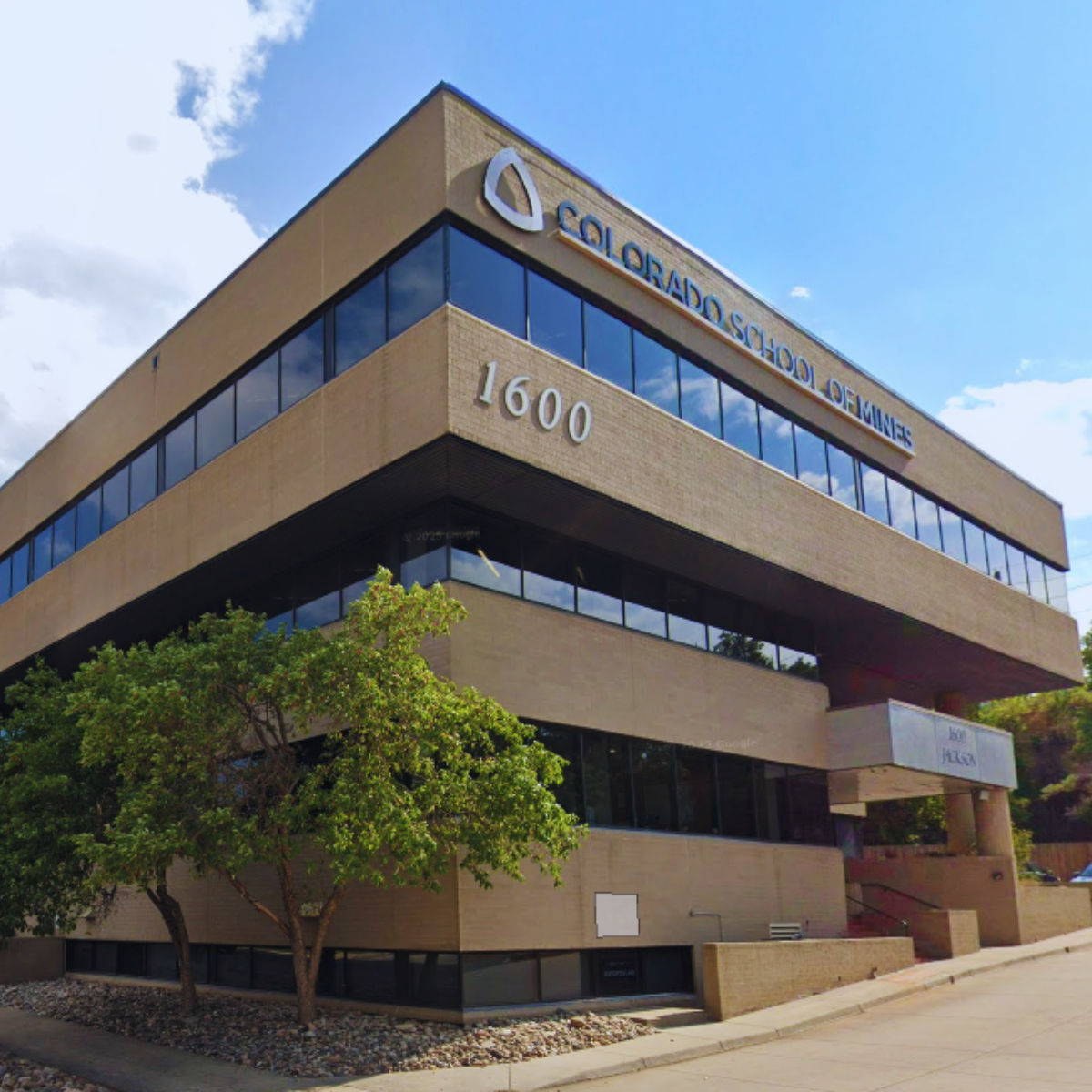 Photo of a modern, multi-story office building with reflective glass windows, located at 1600 and bearing a sign for Colorado School of Mines.