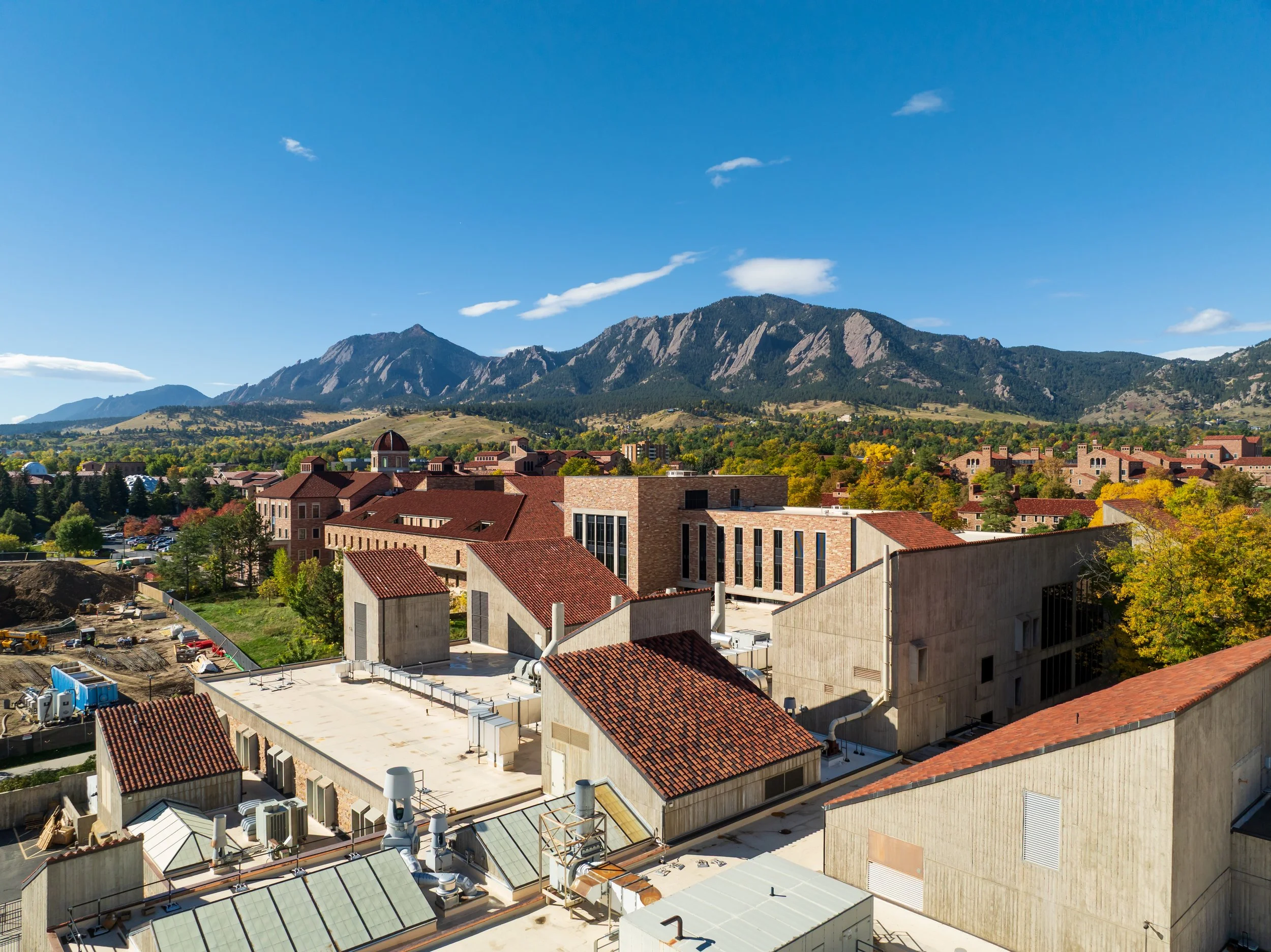 View of buildings with red tile roofs, mountains in the background, and a clear blue sky.