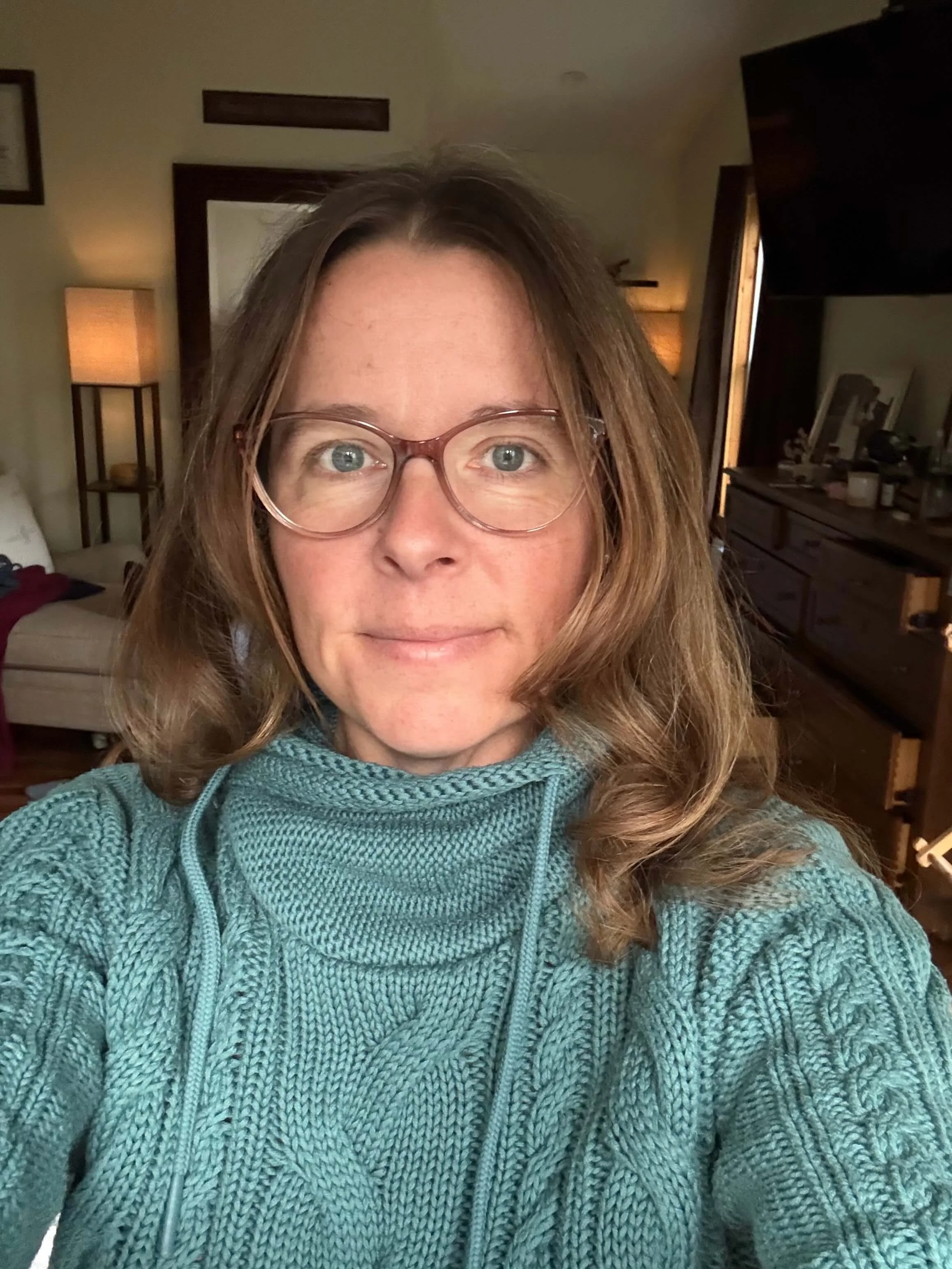 Close up photo of a woman with glasses, long hair and blue sweater