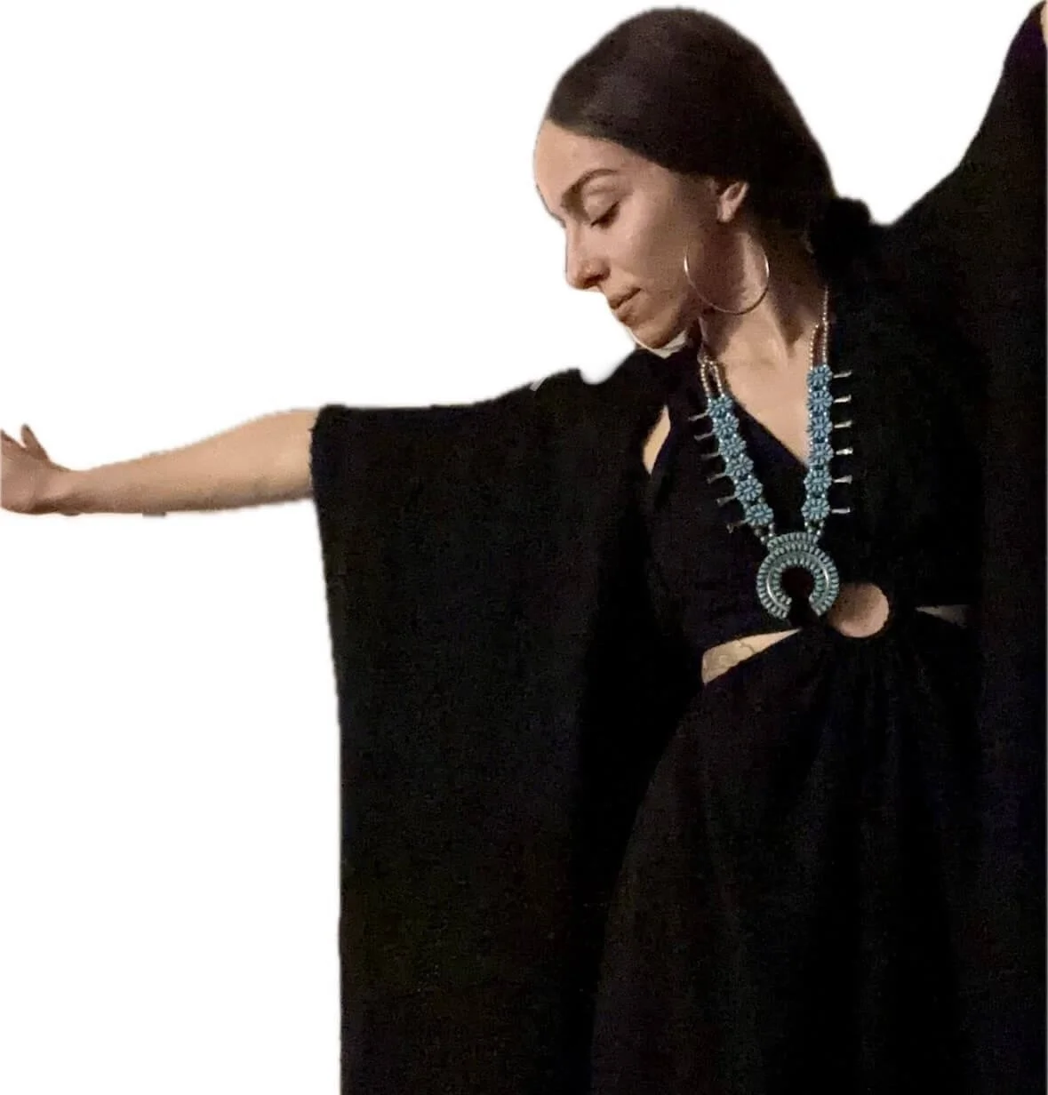 A dark haired woman wearing a black flowing outfit holds her arm out to the side