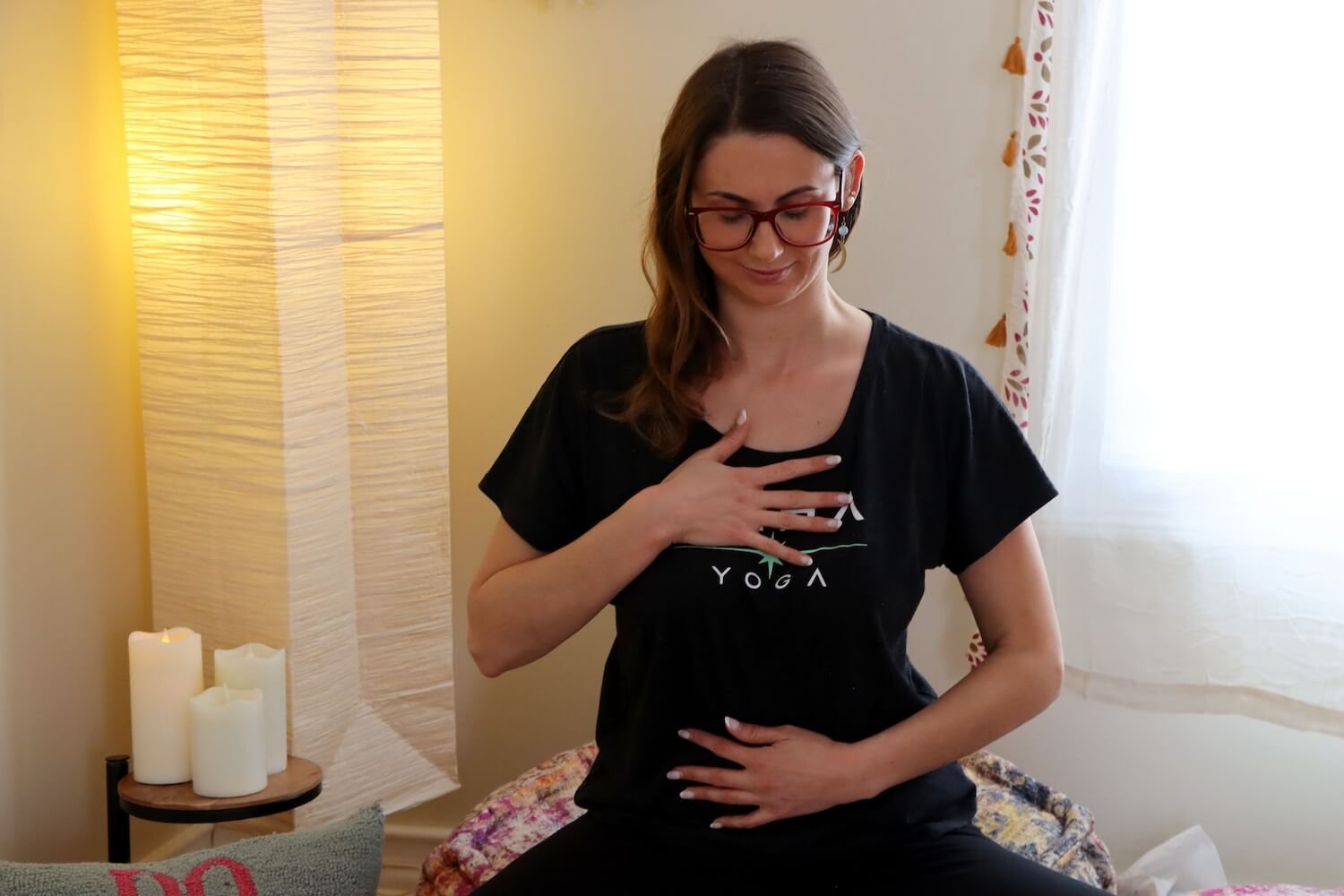 A woman in a Saha Yoga shirt holds her hands on her torso and chest