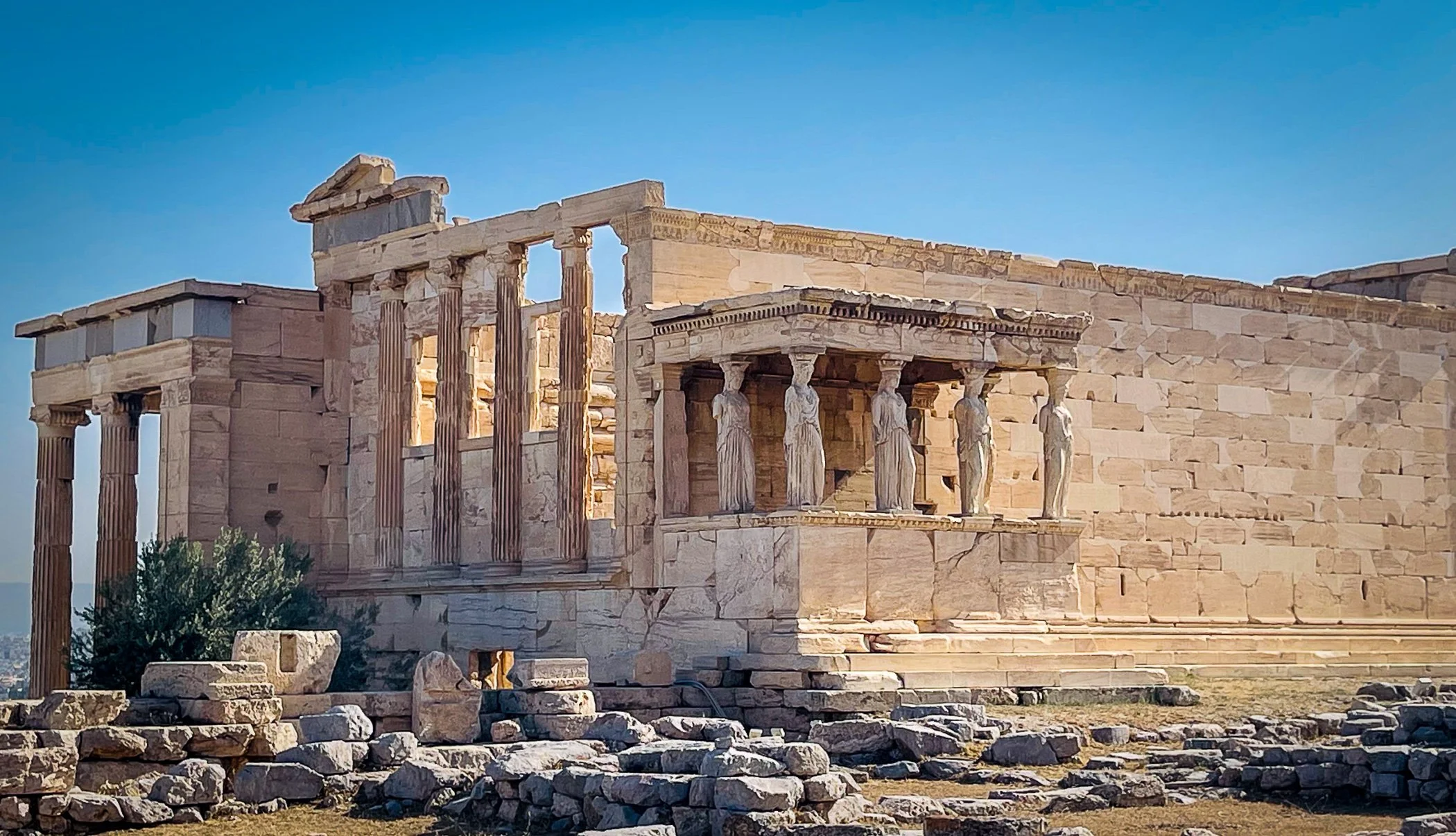 Ancient Greek ruins of the Parthenon with columns, stone blocks, and a clear blue sky.