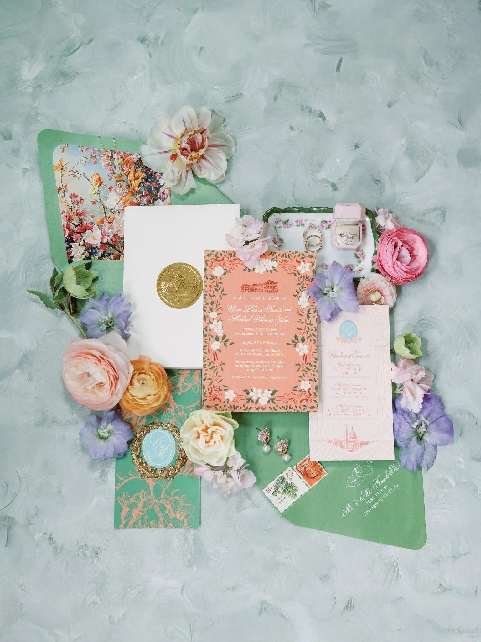 Wedding invitation suite with flowers, rings, and decorative elements on a light background.