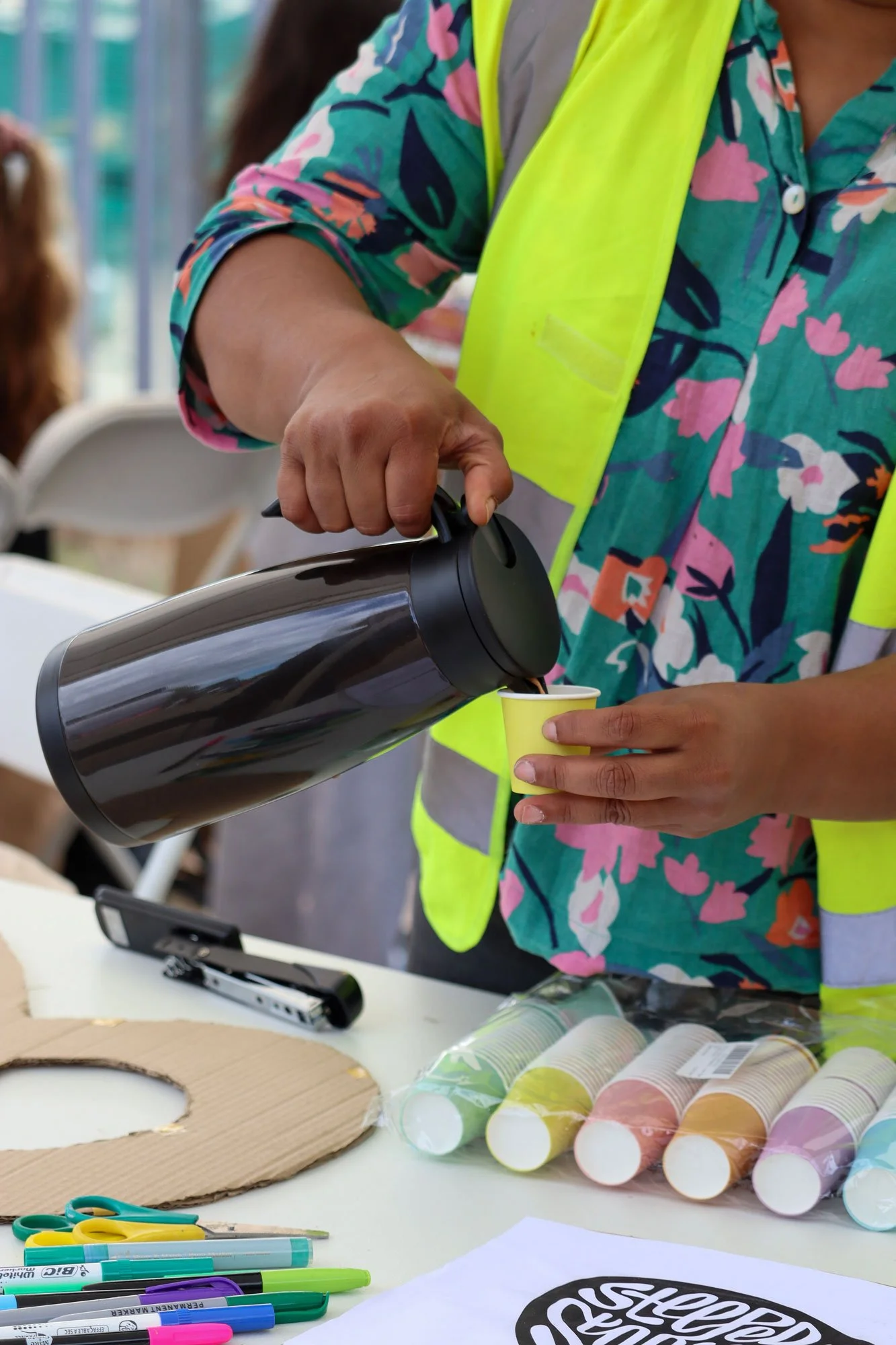 Anisha pouring hot chai in a paper cup for one of the participants.