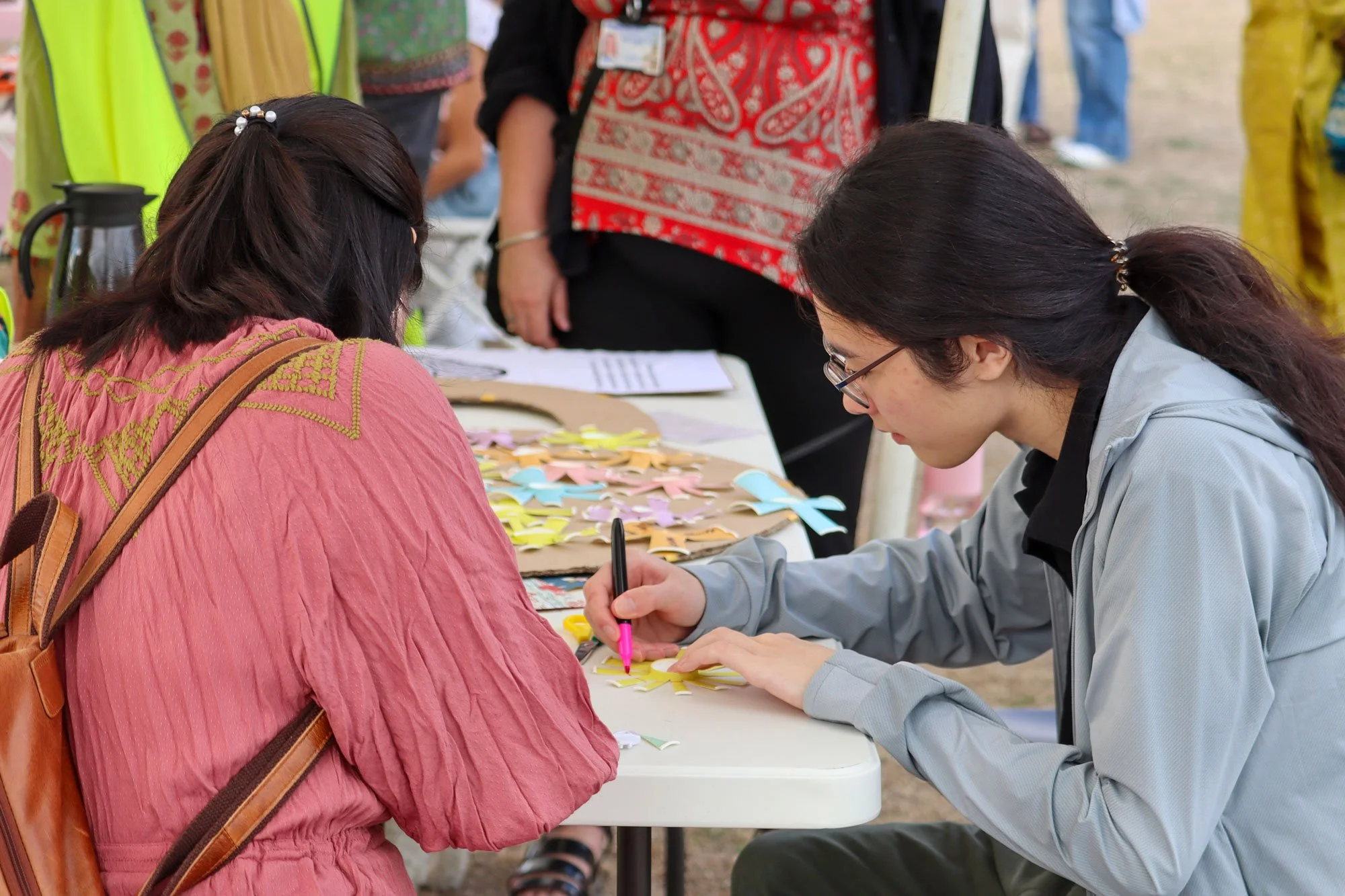 People writing/drawing their experiences on the cut-up paper tea cups.