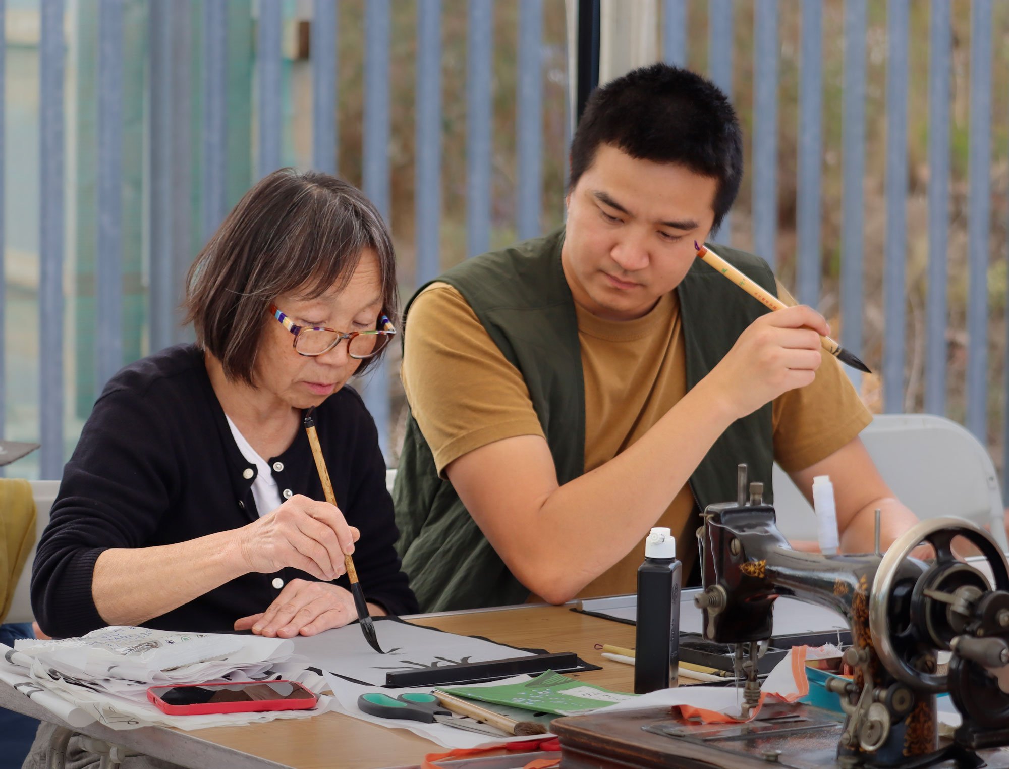 Yoshiko demonstrating Japanese calligraphy to an eager participant.