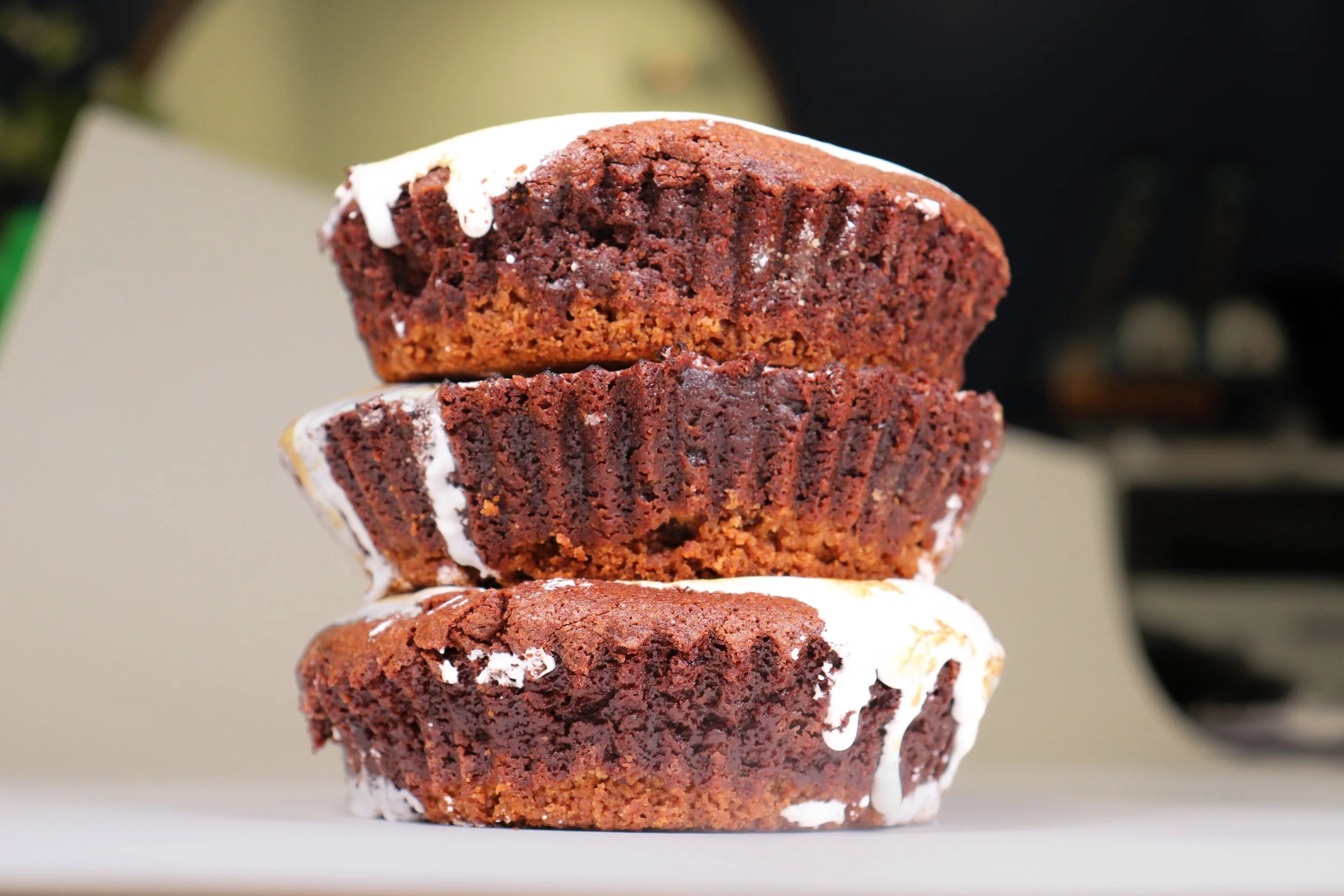 Stacked chocolate muffins with white icing on top, close-up view.
