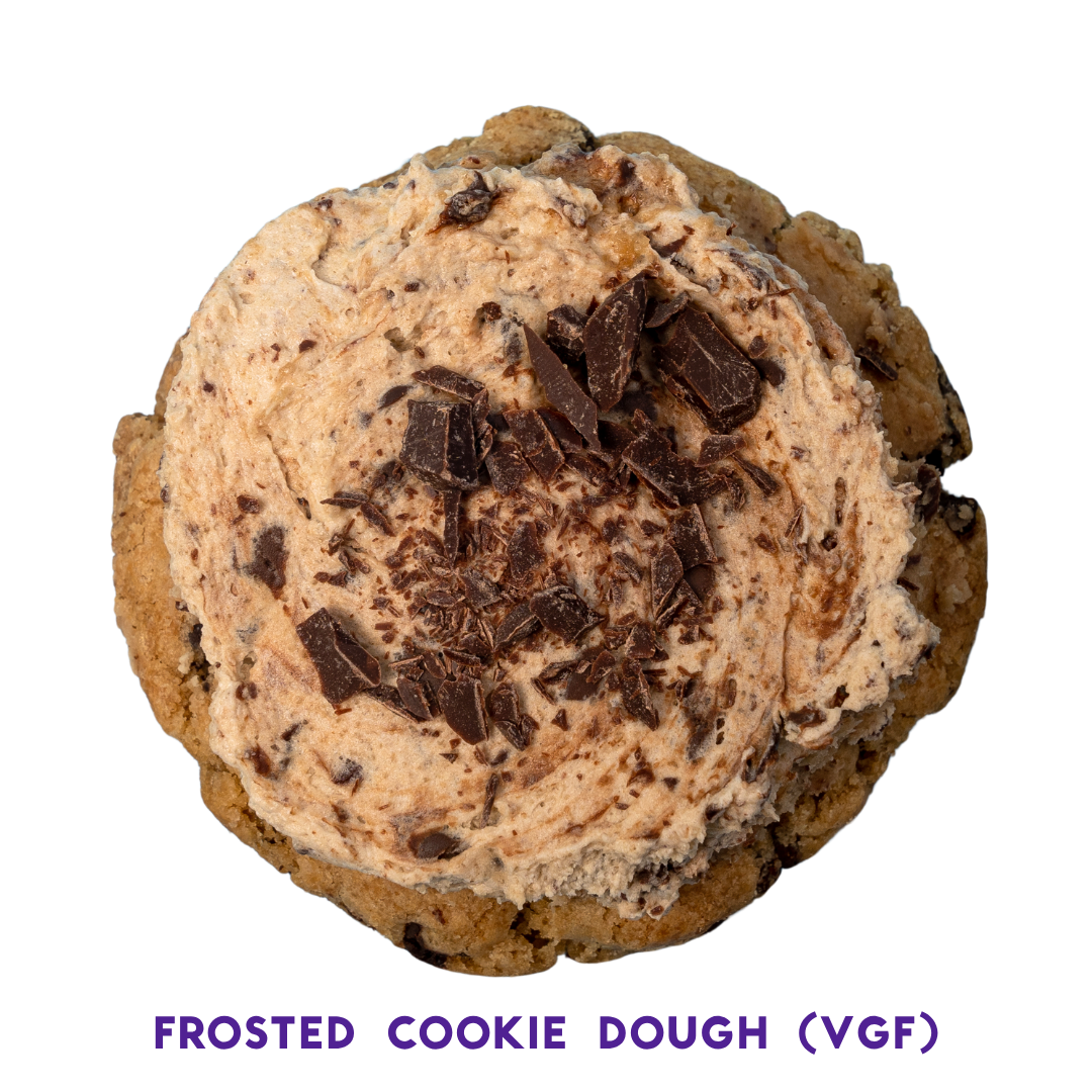 Close-up of a chocolate chip cookie topped with a scoop of chocolate chip ice cream and chocolate shavings.
