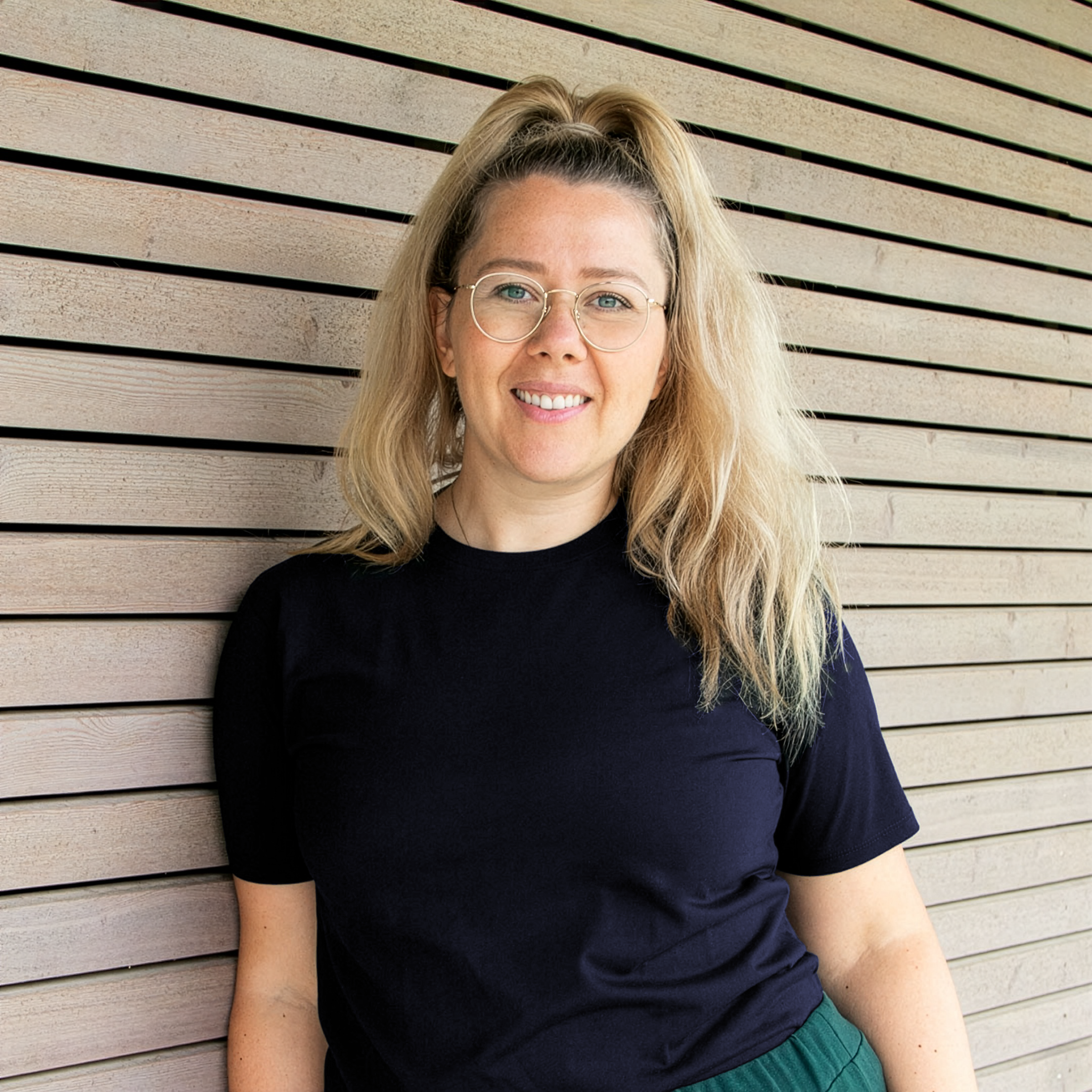 Projektmanagerin Sarah Winter lehnt vor Holzwand