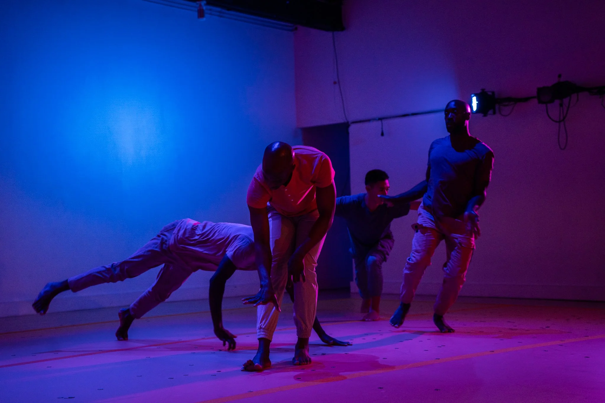 Four dancers performing ensemble movement under blue and purple lighting in The Righteous Beauty of the Things Never Accounted For