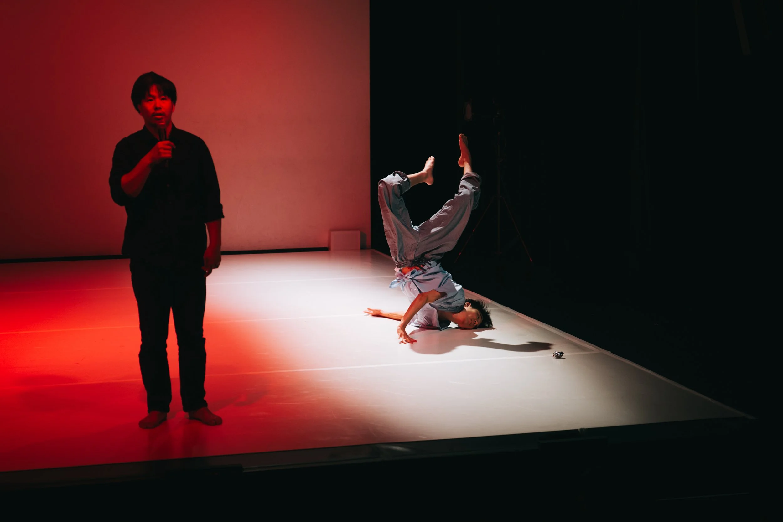 Daiki Sogawa performing floor movement while Kazuma Yamamoto holds a microphone in Total Beings | Burning Hearts.
