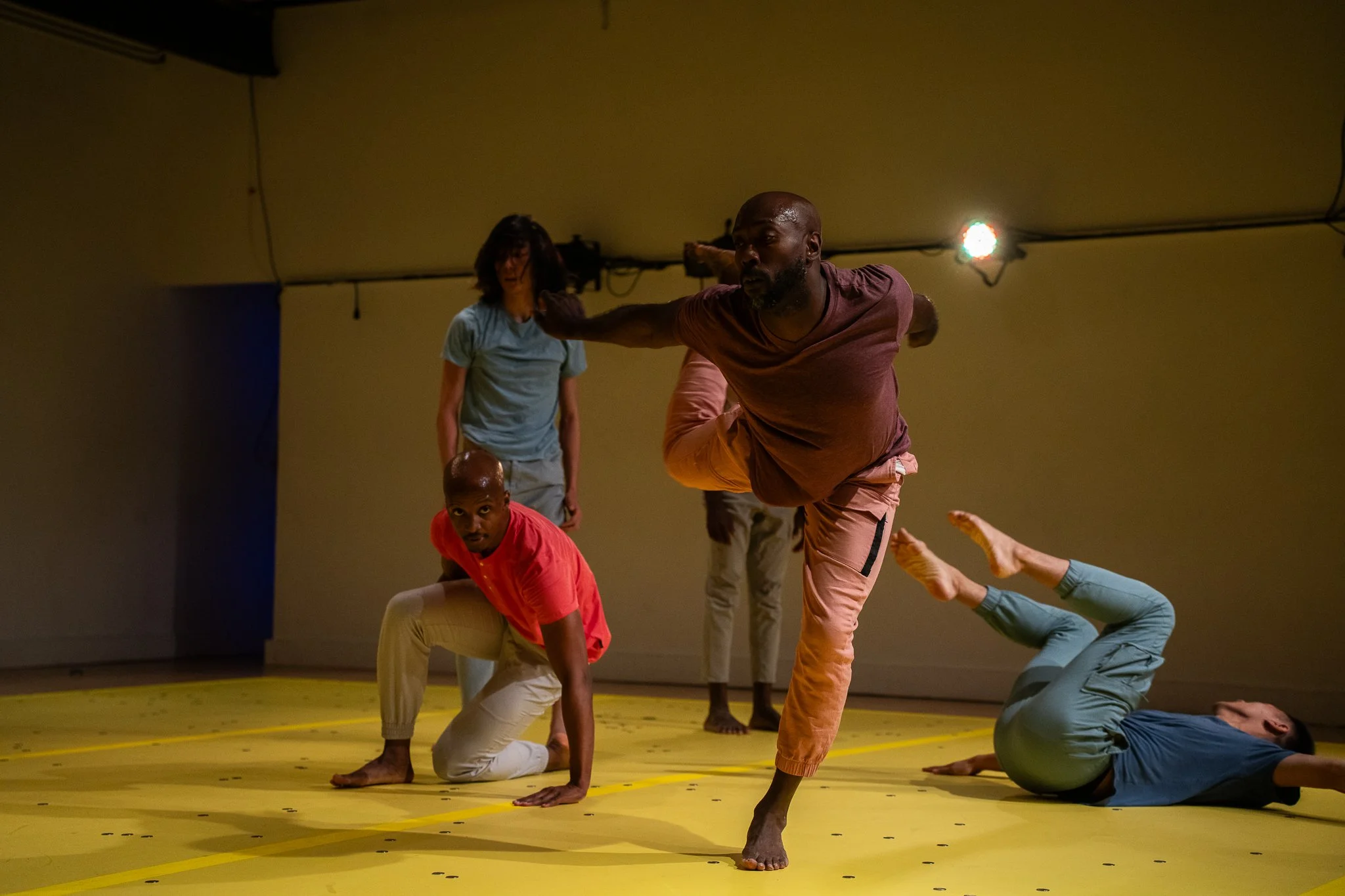 Five dancers improvising together on a yellow floor scattered with coins in The Righteous Beauty of the Things Never Accounted For.